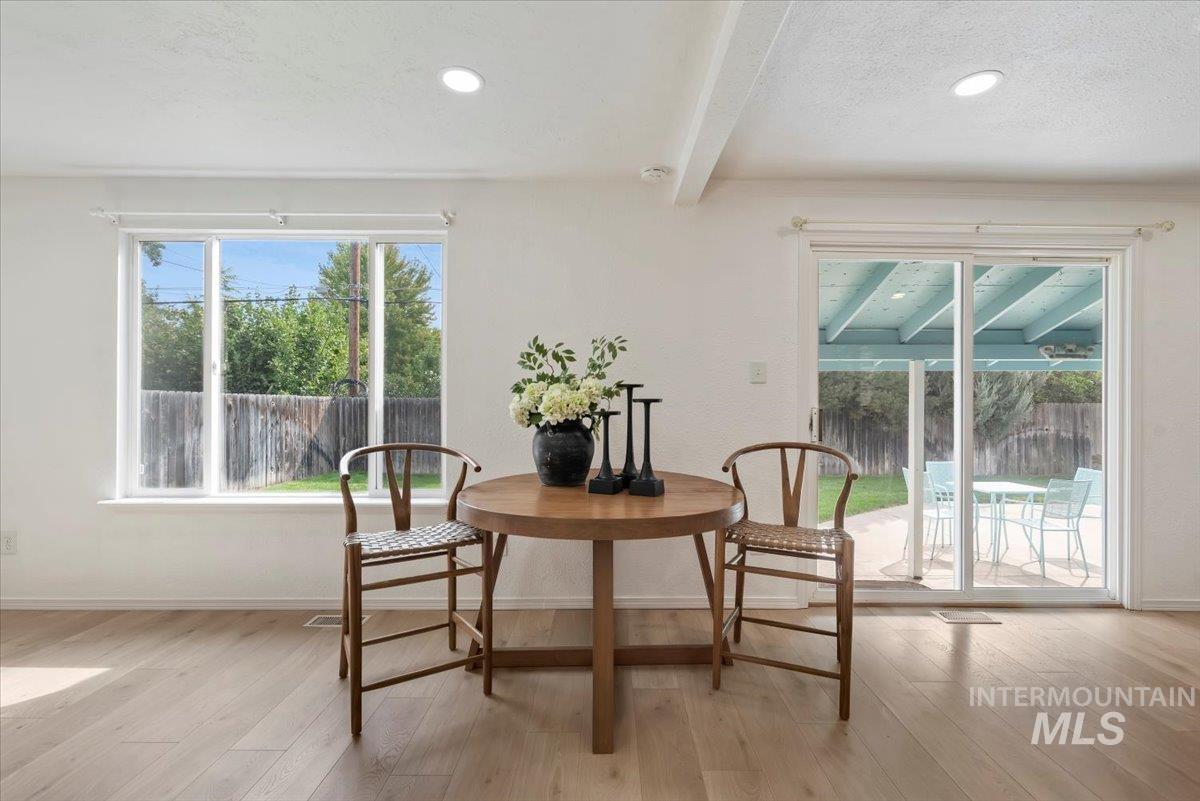 Dining area with beam ceiling, light wood-type flooring, a textured ceiling, and recessed lighting