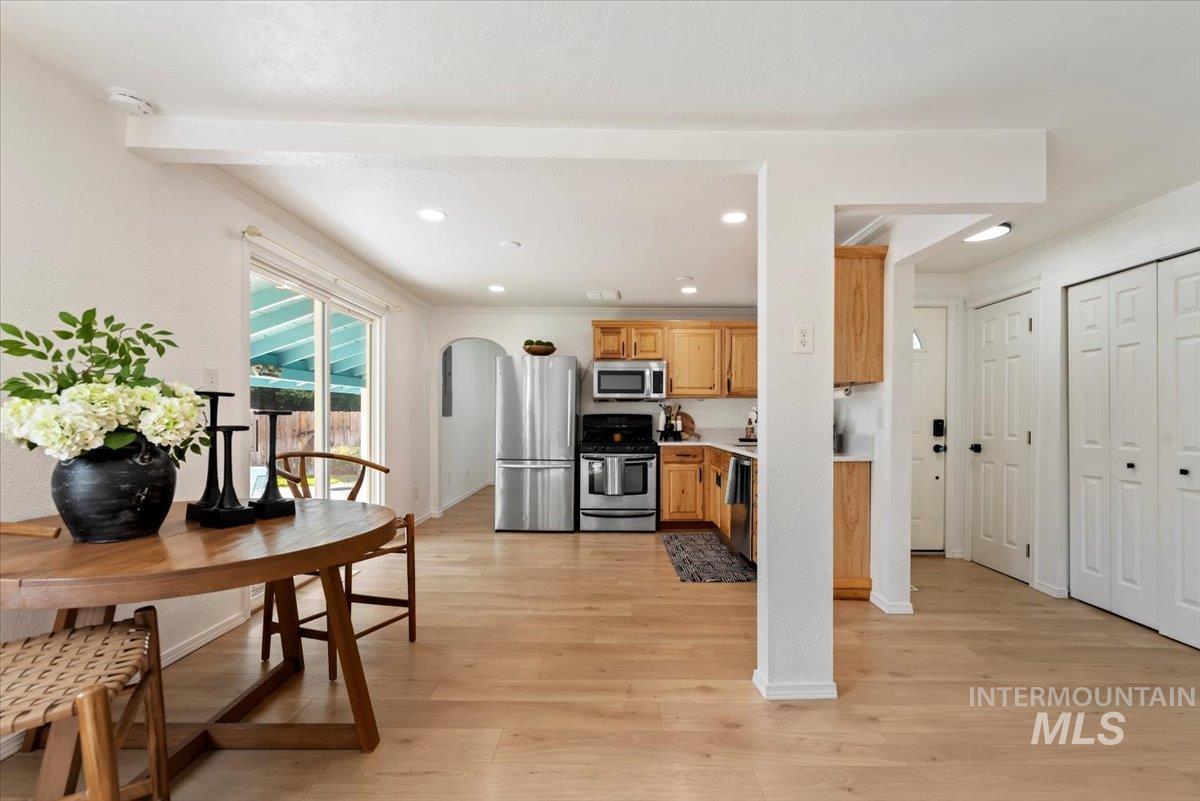 Kitchen featuring arched walkways, stainless steel appliances, light wood-type flooring, light countertops, and recessed lighting