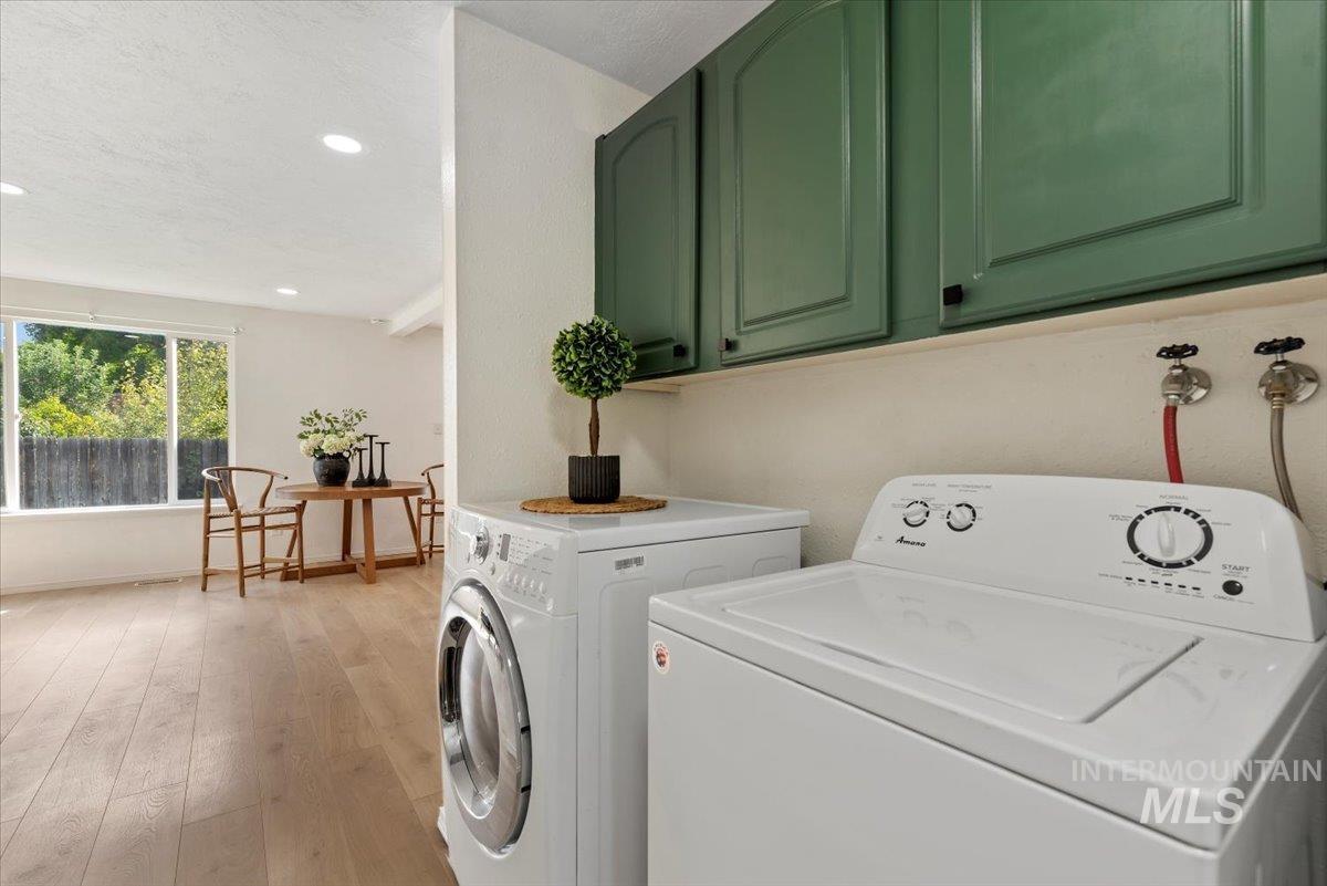 Laundry area with light wood-type flooring, recessed lighting, washing machine and dryer, and cabinet space