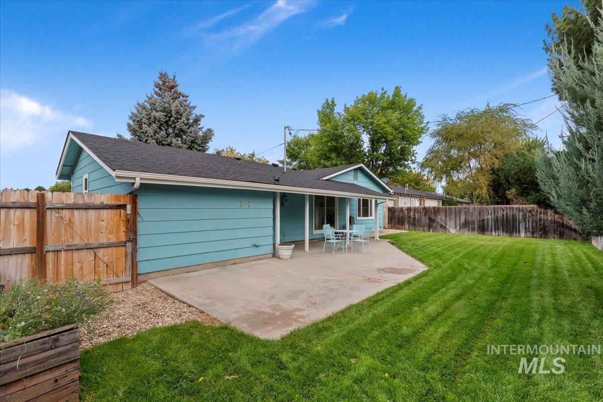 Rear view of house featuring a patio area, a fenced backyard, and roof with shingles