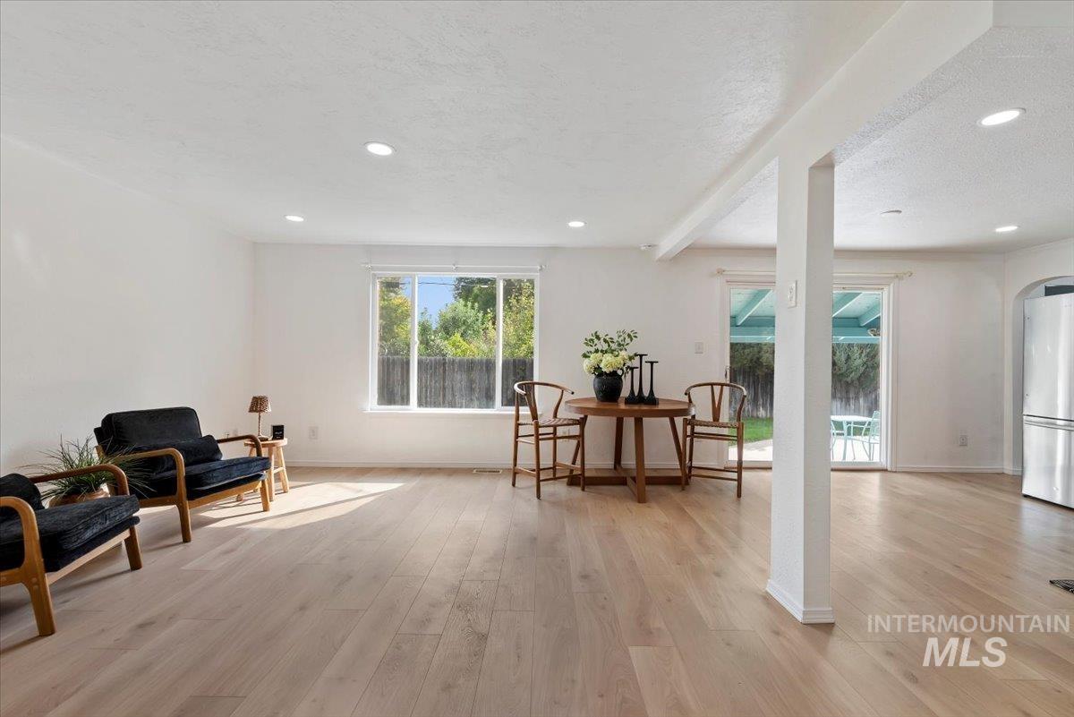 Sitting room featuring arched walkways, light wood finished floors, recessed lighting, a textured ceiling, and beam ceiling