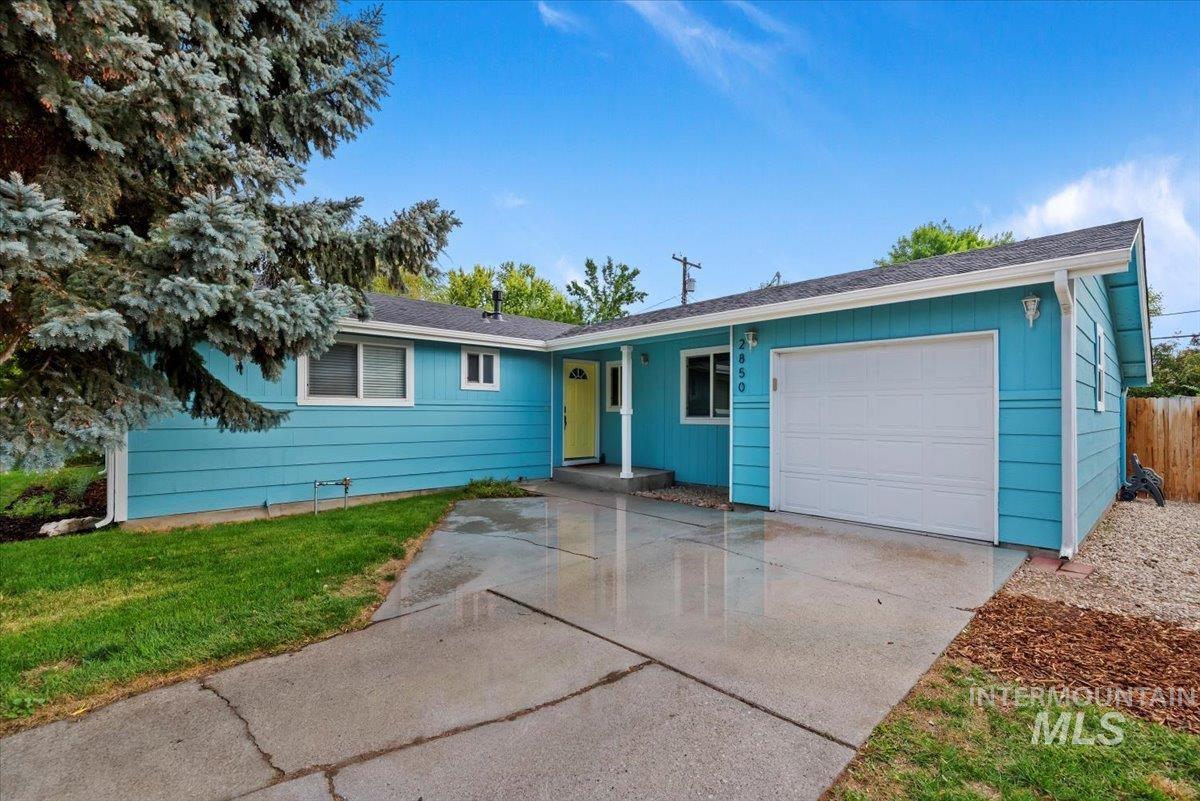 Single story home featuring a garage, driveway, a front lawn, and roof with shingles