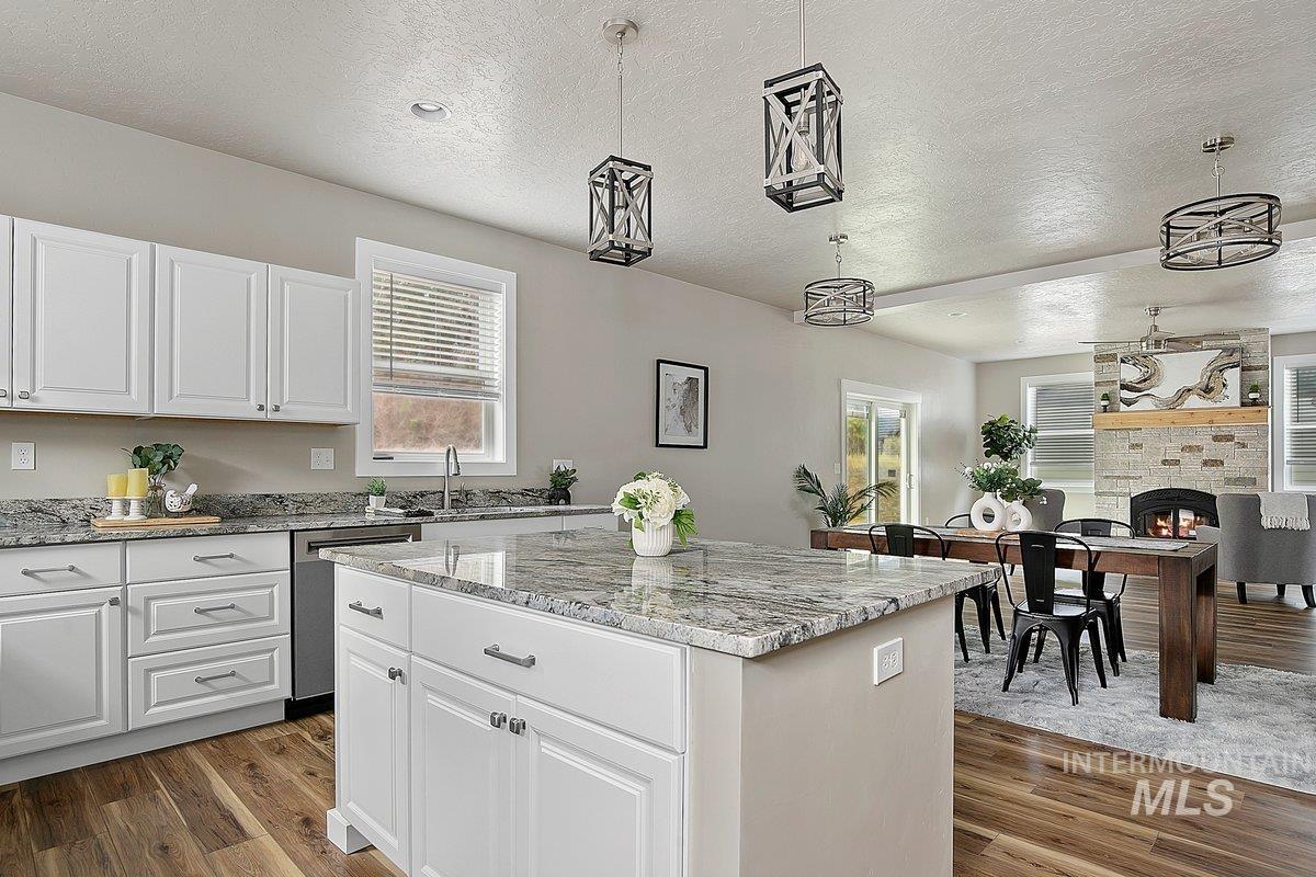 Kitchen with stainless steel dishwasher, laminate floors, a center island, and pendant light fixtures