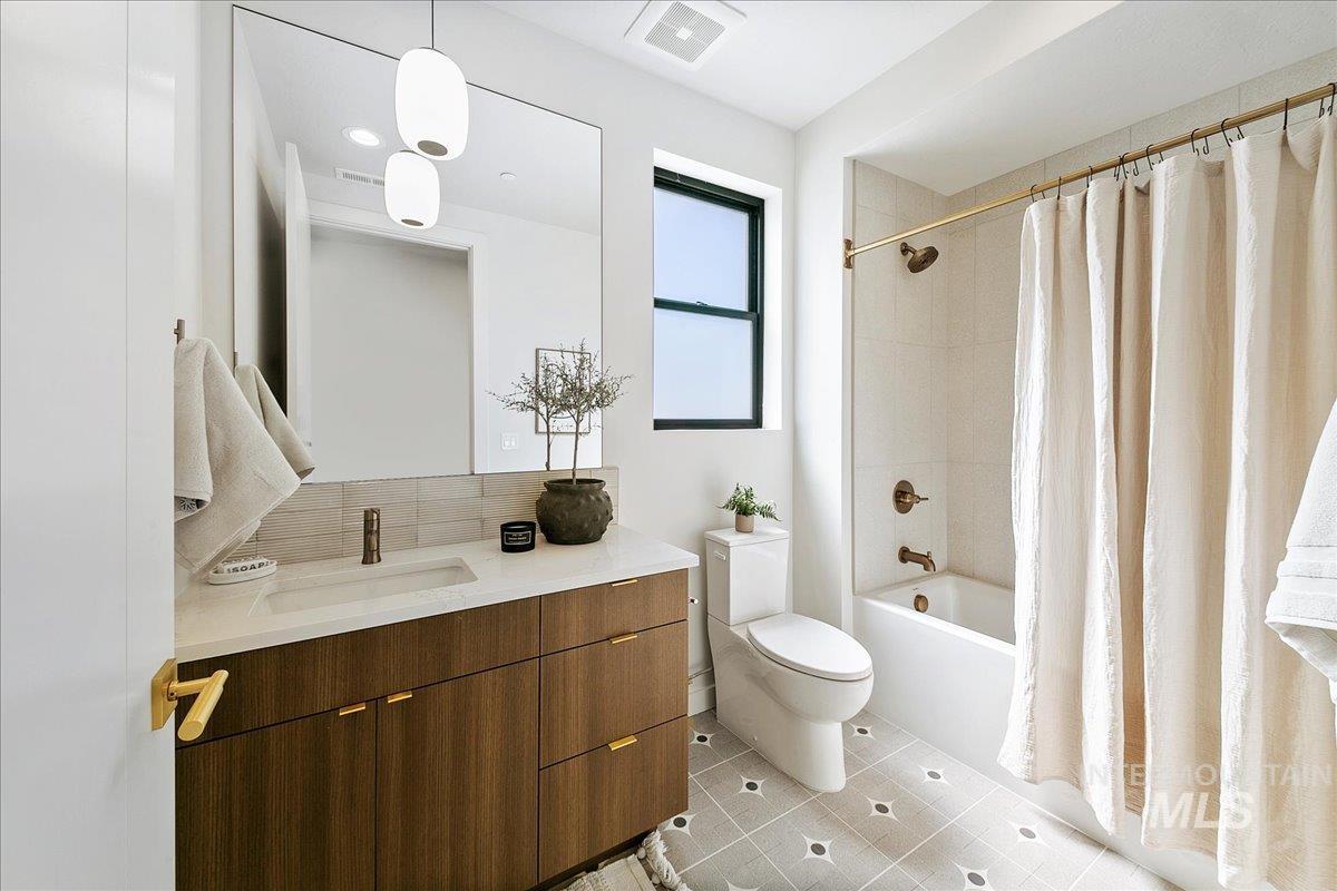Bathroom with vanity, shower / bath combo with shower curtain, and light tile patterned floors