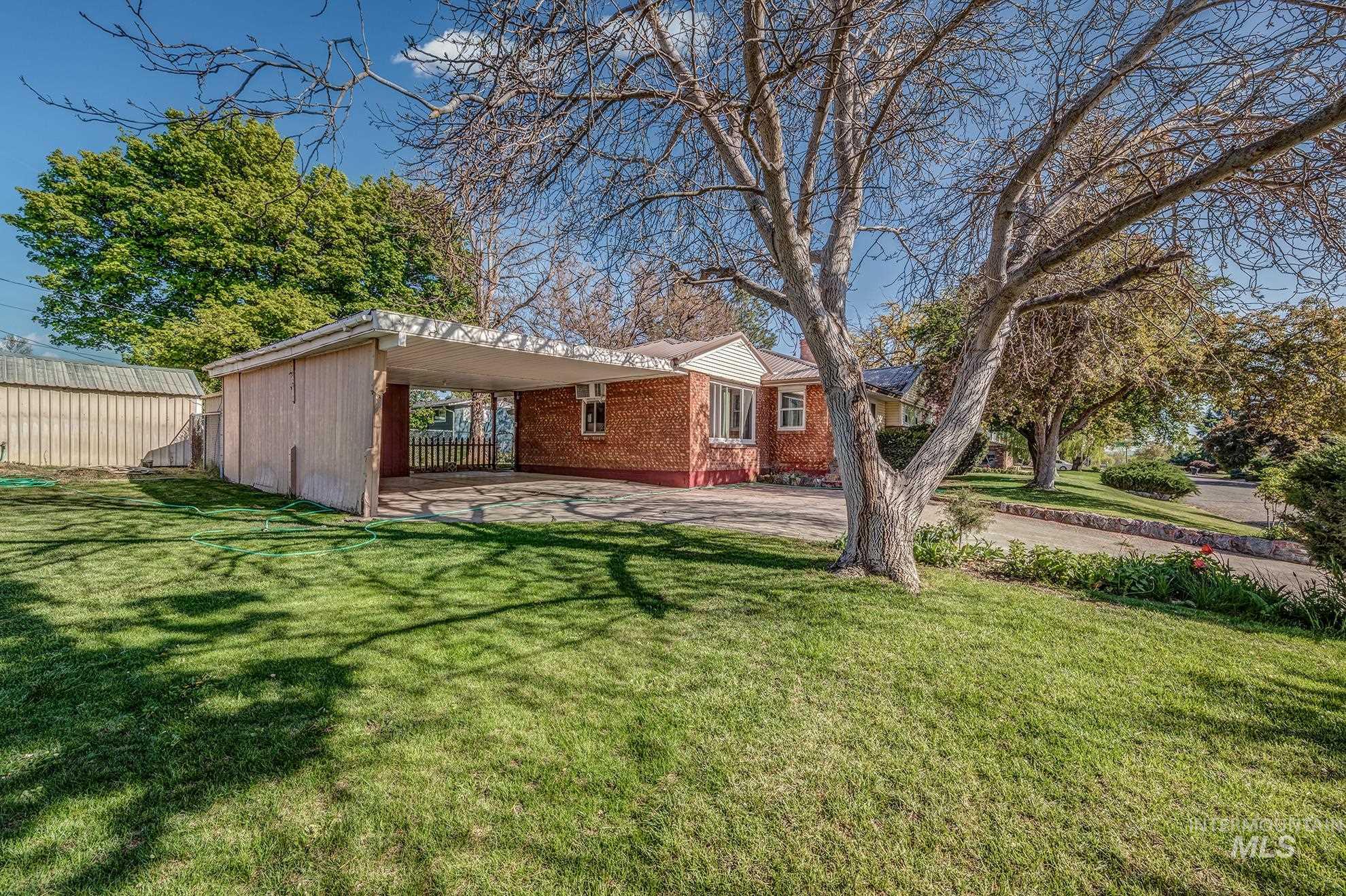 View of front of property featuring a patio area, brick siding, and a carport