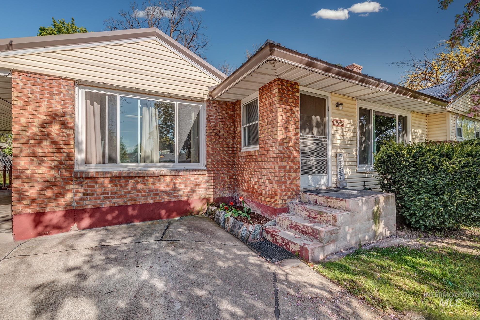 Exterior featuring a brick and siding facade, covered entry, concrete steps, and a large front window