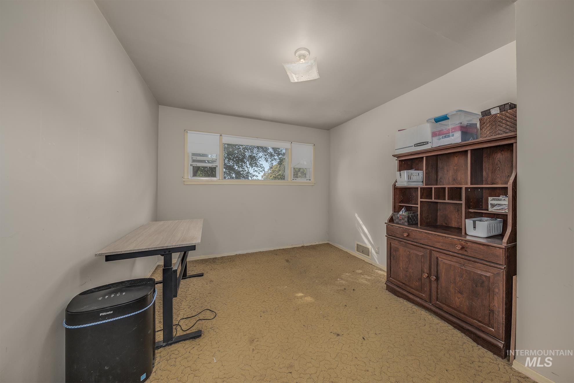 Office space with baseboards and light carpet