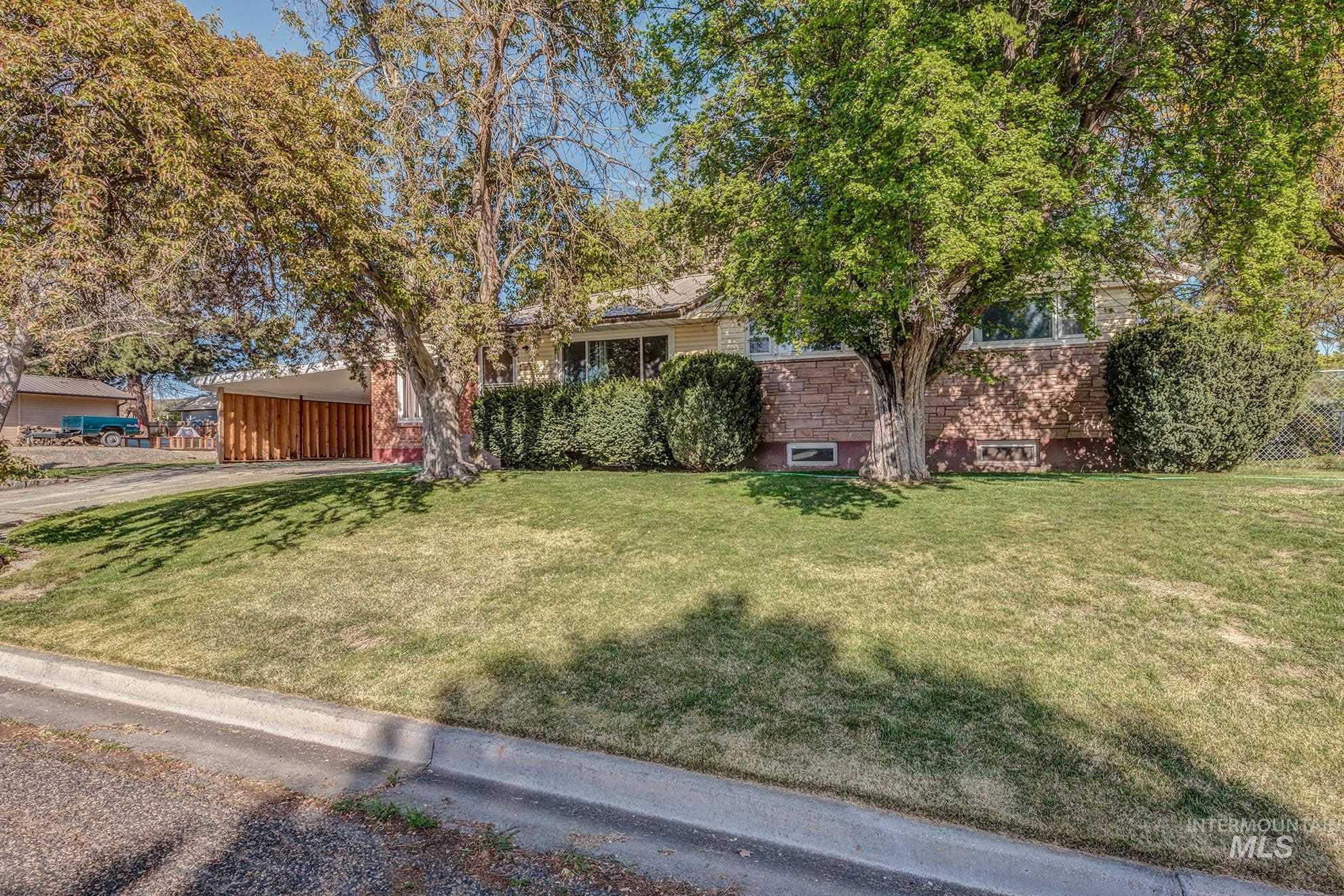 View of property hidden behind natural elements with a front yard