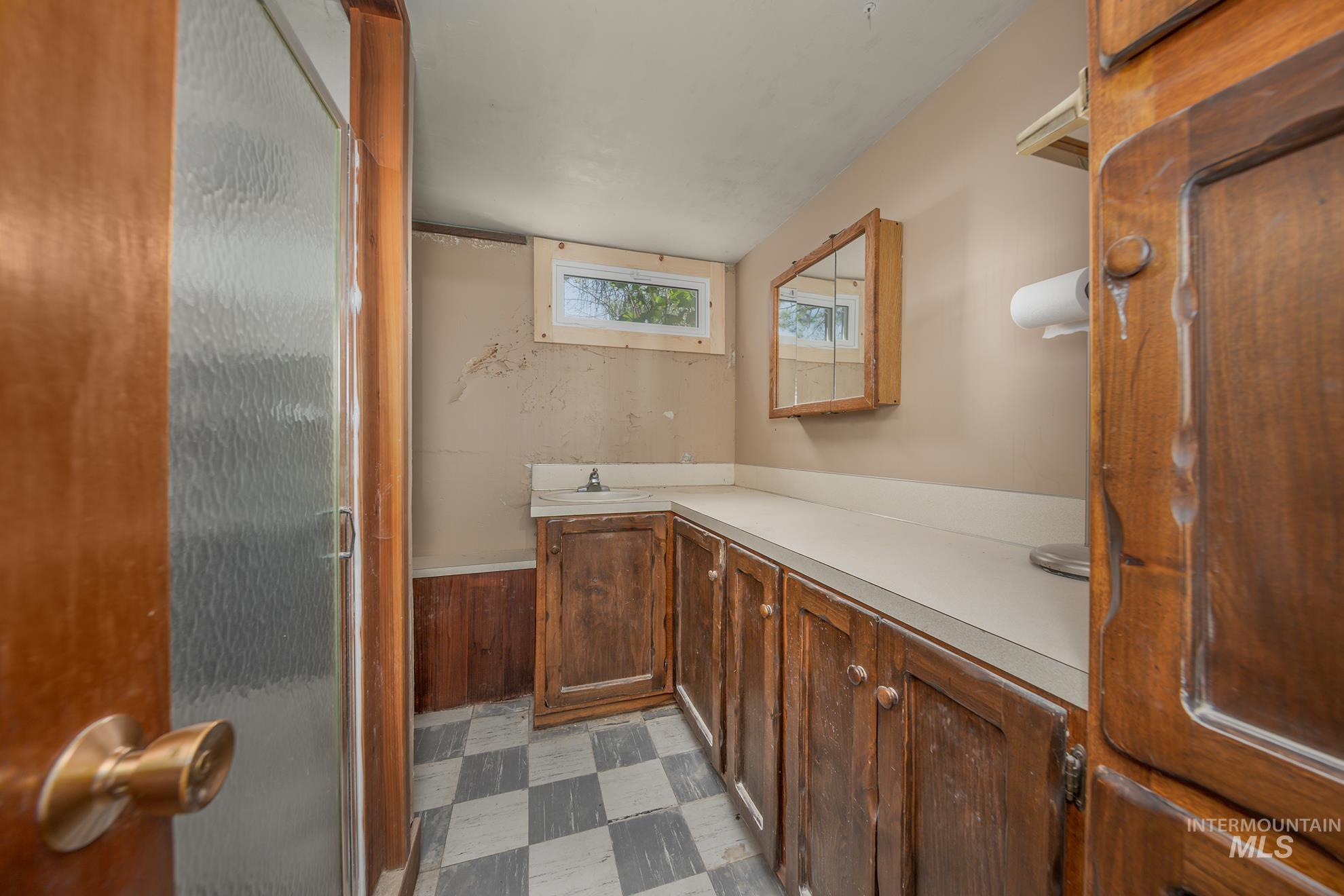 Bathroom featuring light floors, vanity, and a shower with shower door