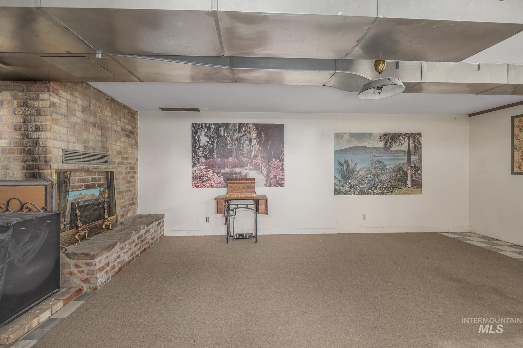 Unfurnished living room with a brick fireplace and carpet floors