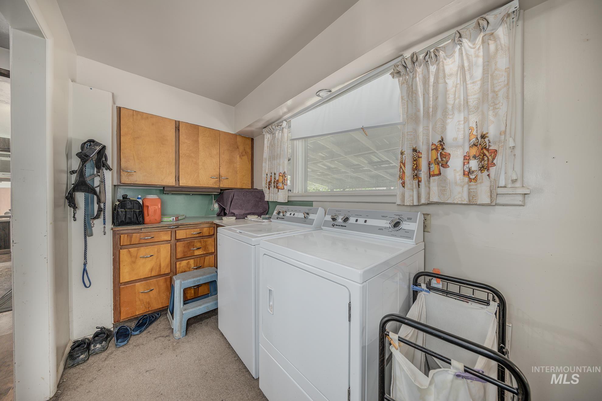 Laundry area with separate washer and dryer, cabinet space, and light colored carpet