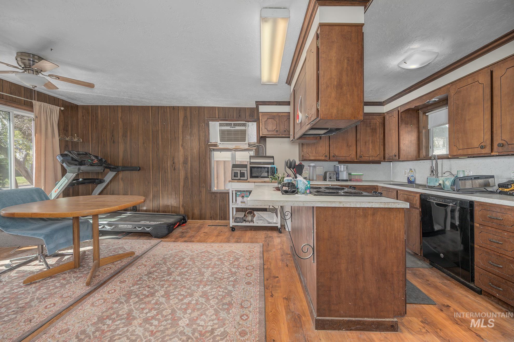 Kitchen featuring light countertops, light wood-type flooring, wood finish cabinets, a ceiling fan, and dishwasher