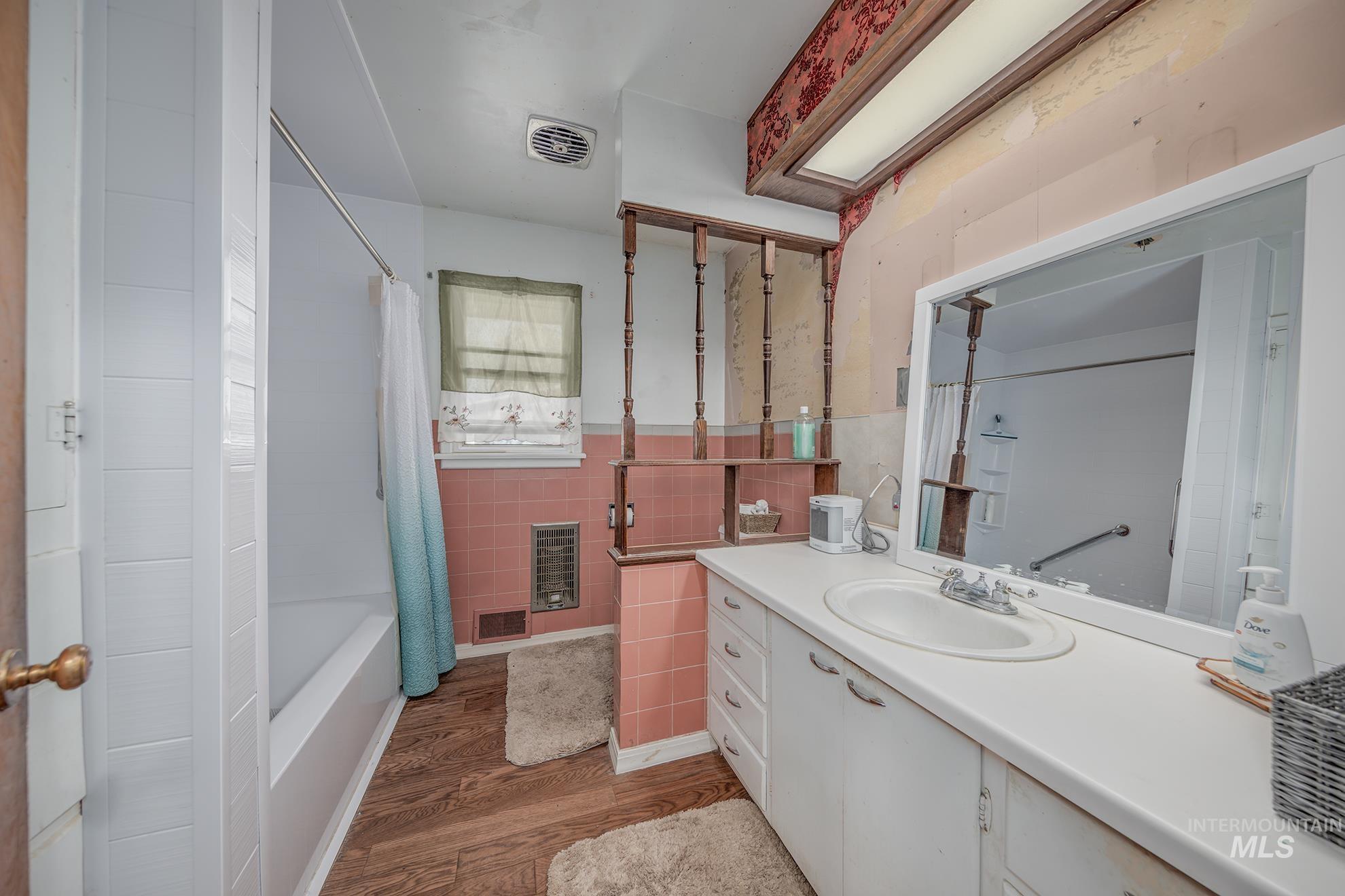 Bathroom featuring vanity, dark wood finished floors, shower / tub combo with curtain, and tile walls