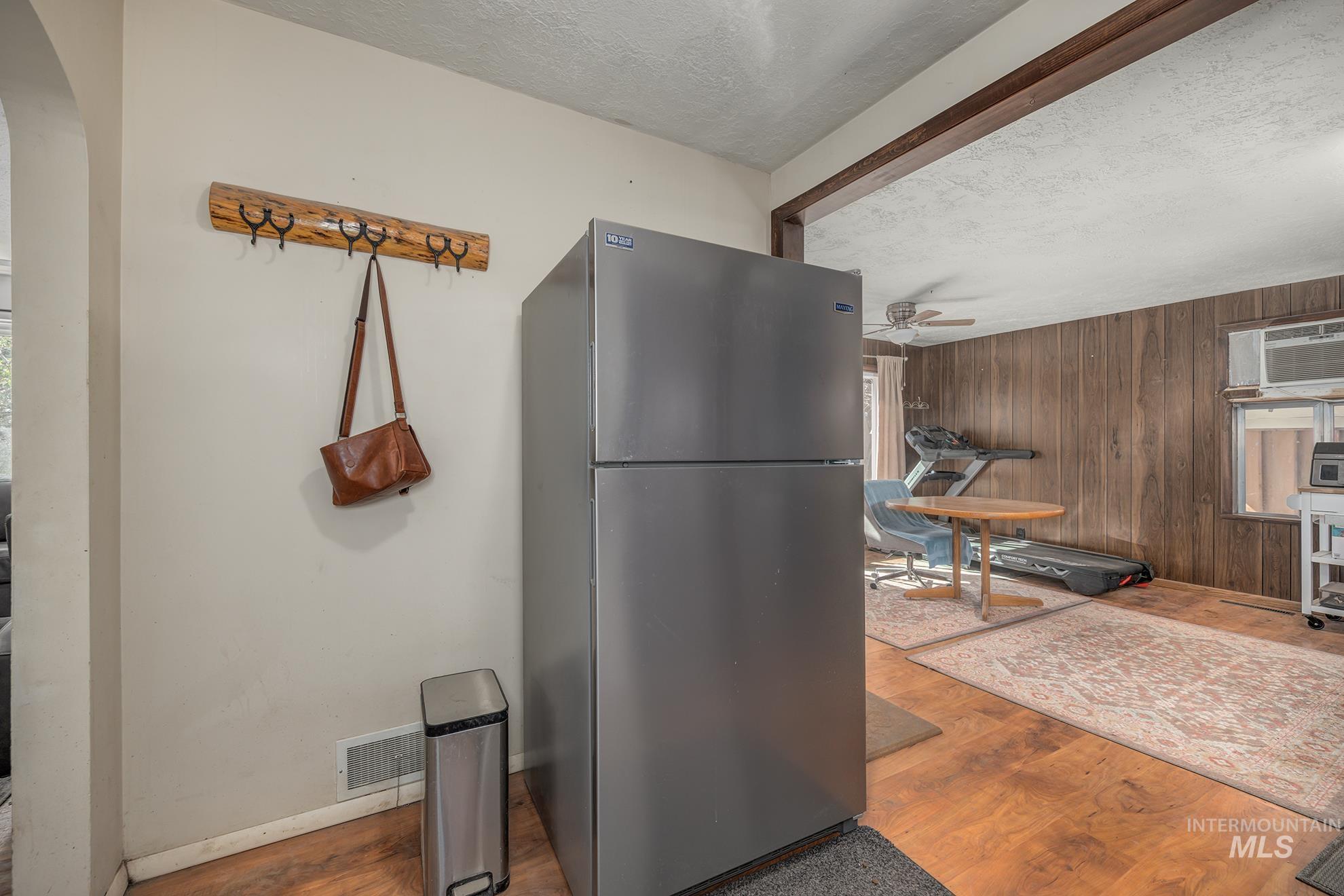Kitchen with freestanding refrigerator, wood finished floors, a textured ceiling, wood walls, and arched walkways