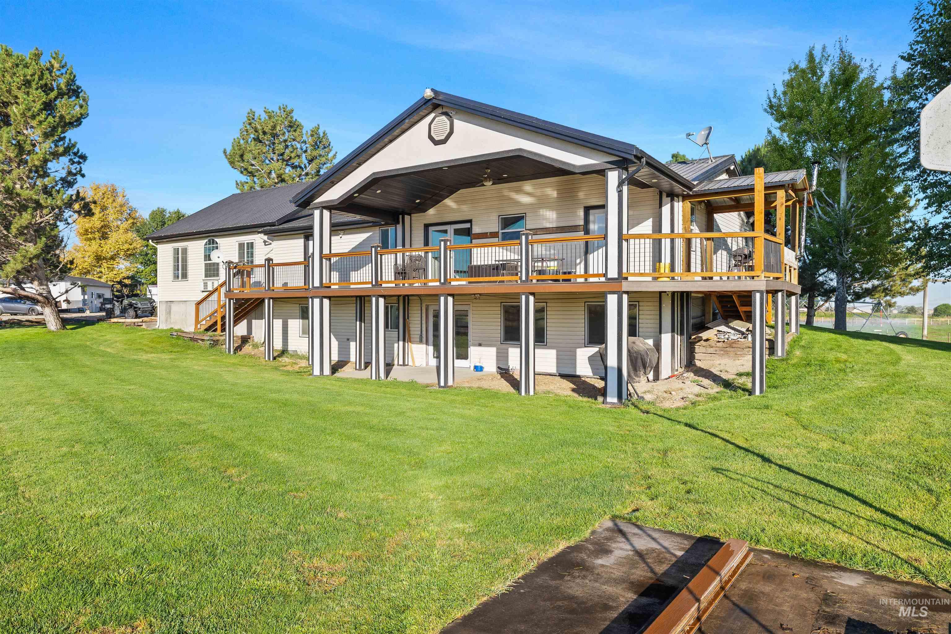 Back of property with a wooden deck, a yard, a patio area, and stairs