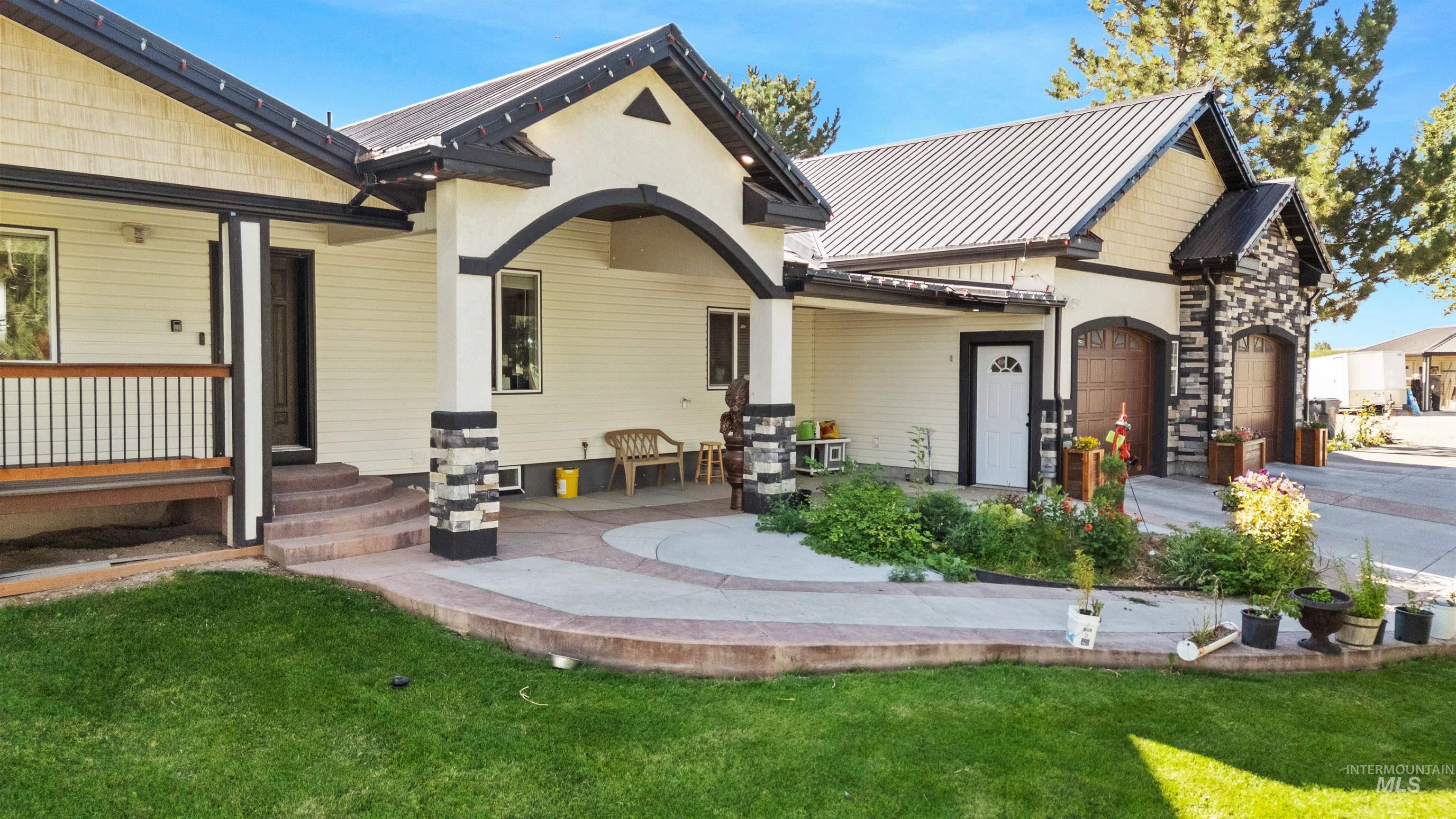 Back of property with a standing seam roof, a metal roof, an attached garage, a lawn, and stucco siding