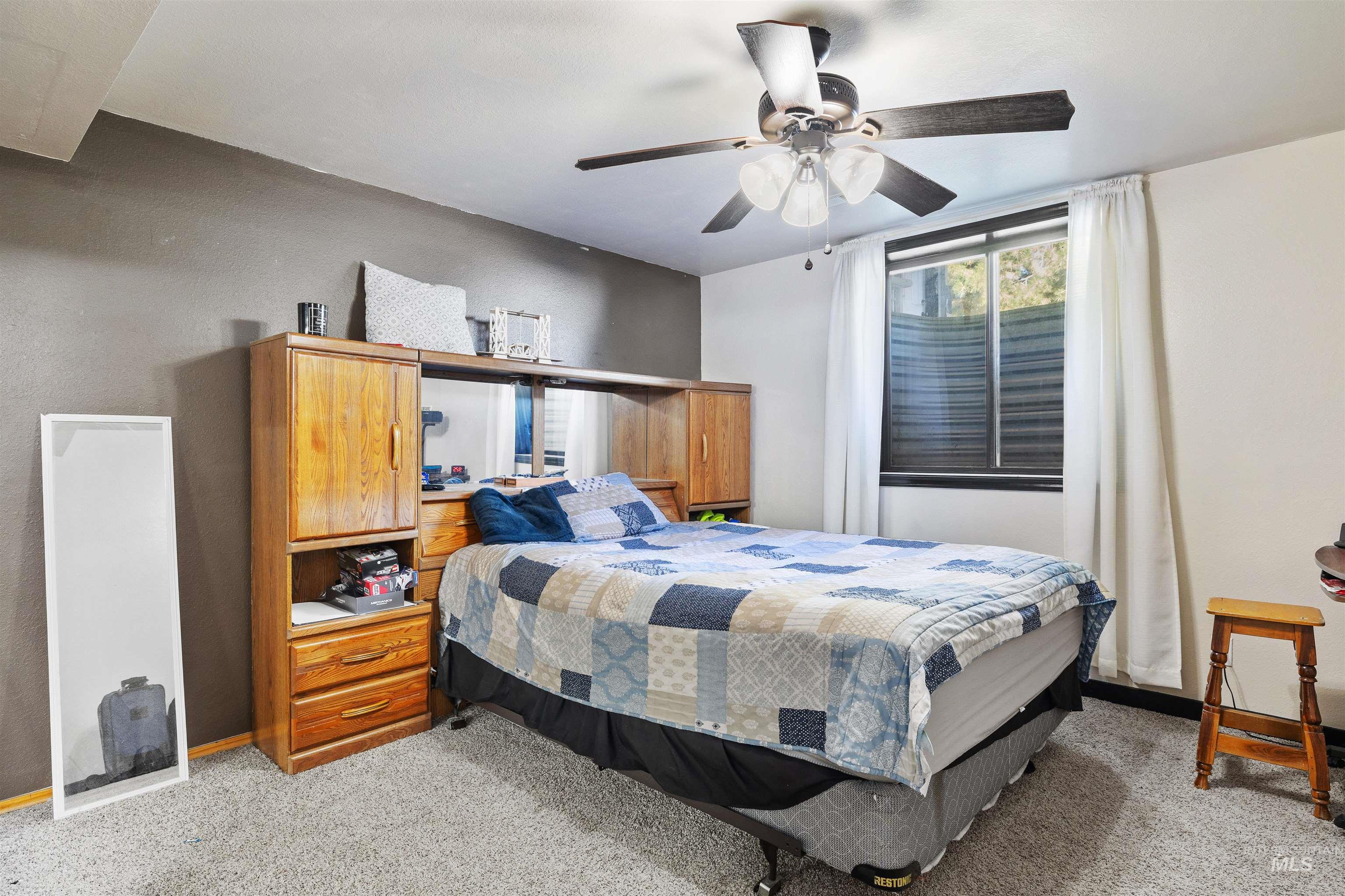 Bedroom with light colored carpet and a ceiling fan
