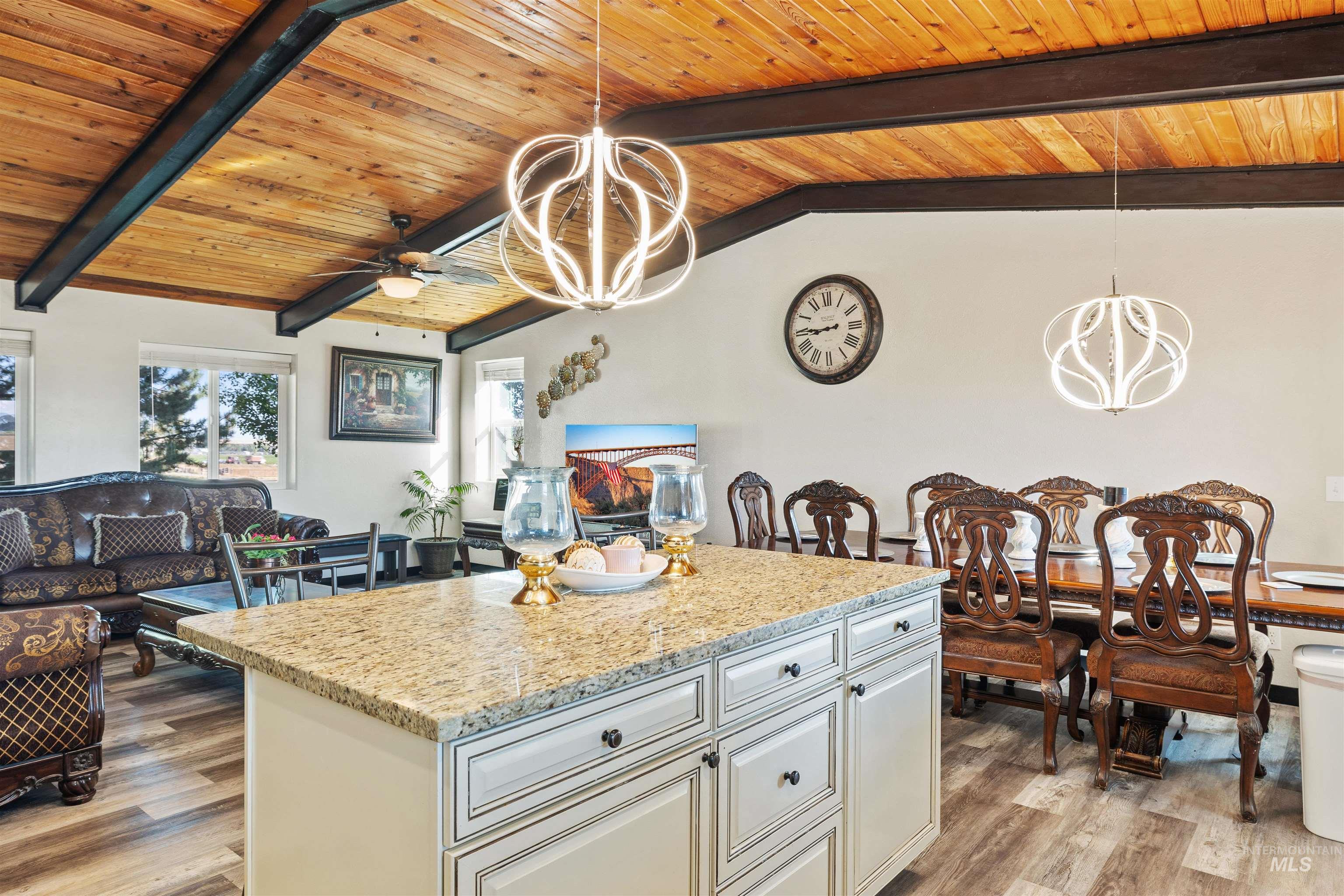 Kitchen with hanging light fixtures, wood ceiling, a chandelier, a center island, and light stone countertops