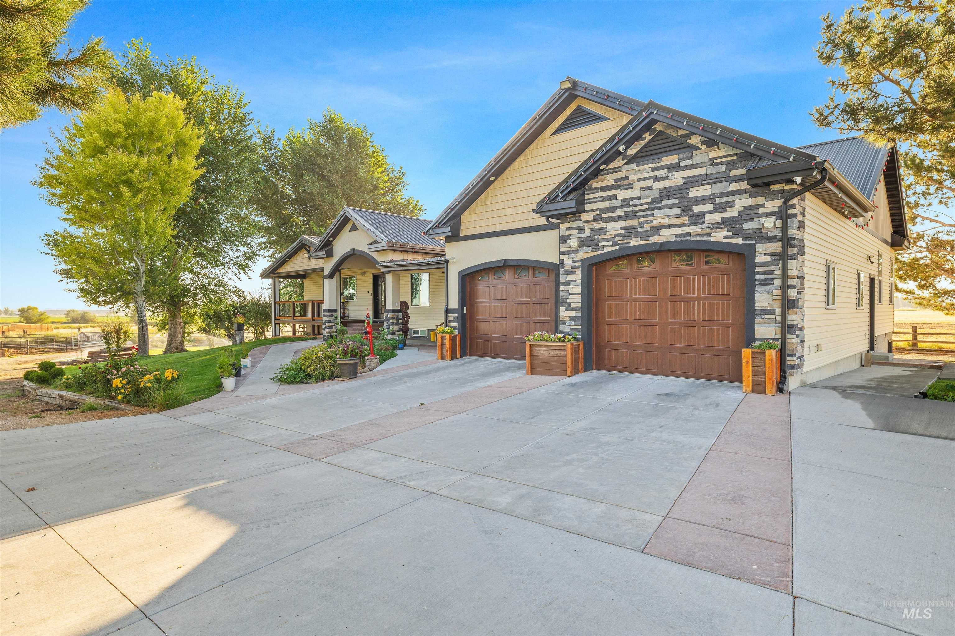 Craftsman-style home with stone siding, a garage, concrete driveway, a metal roof, and covered porch