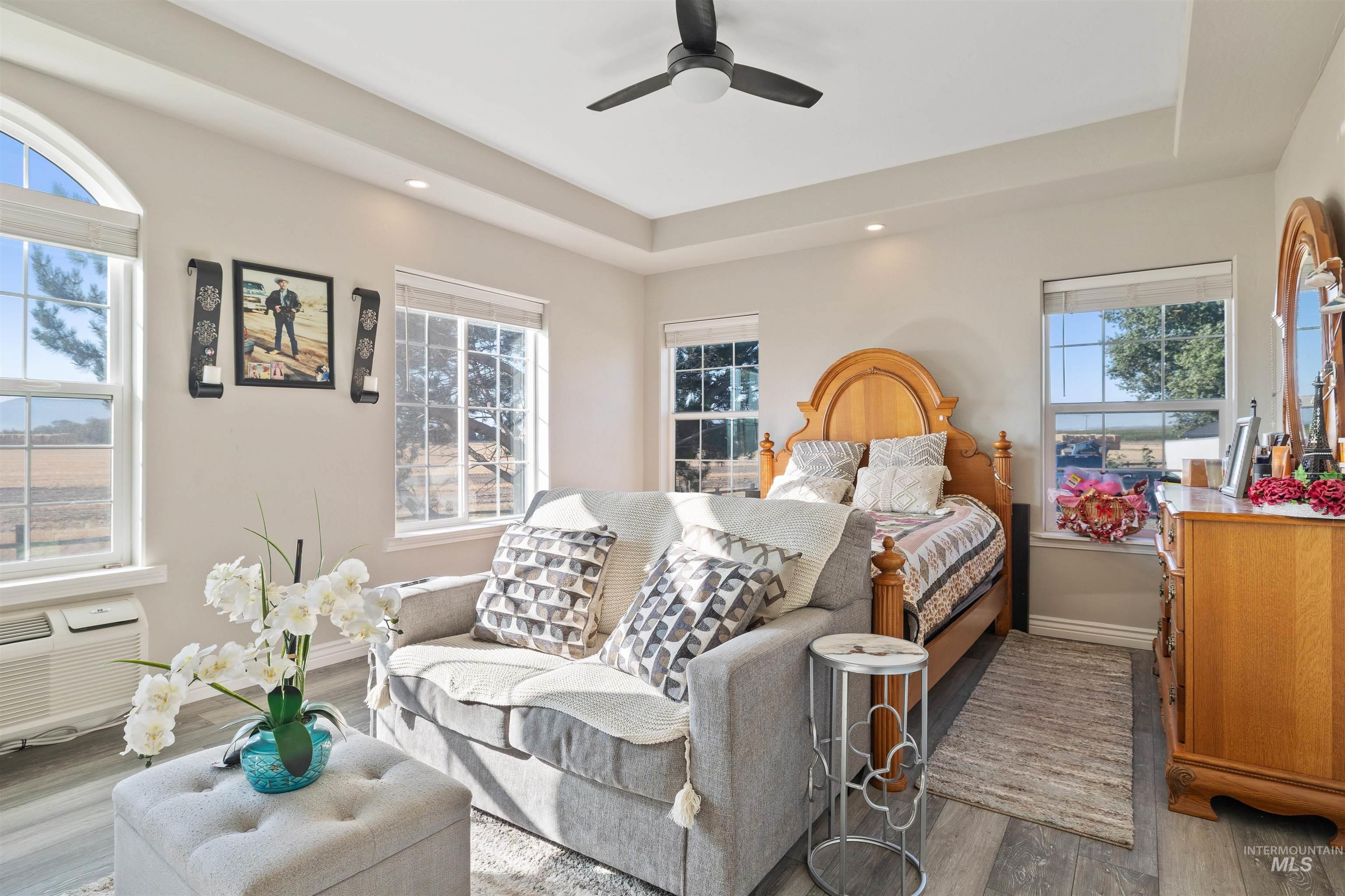 Bedroom with wood finished floors, a raised ceiling, ceiling fan, recessed lighting, and a wall mounted air conditioner
