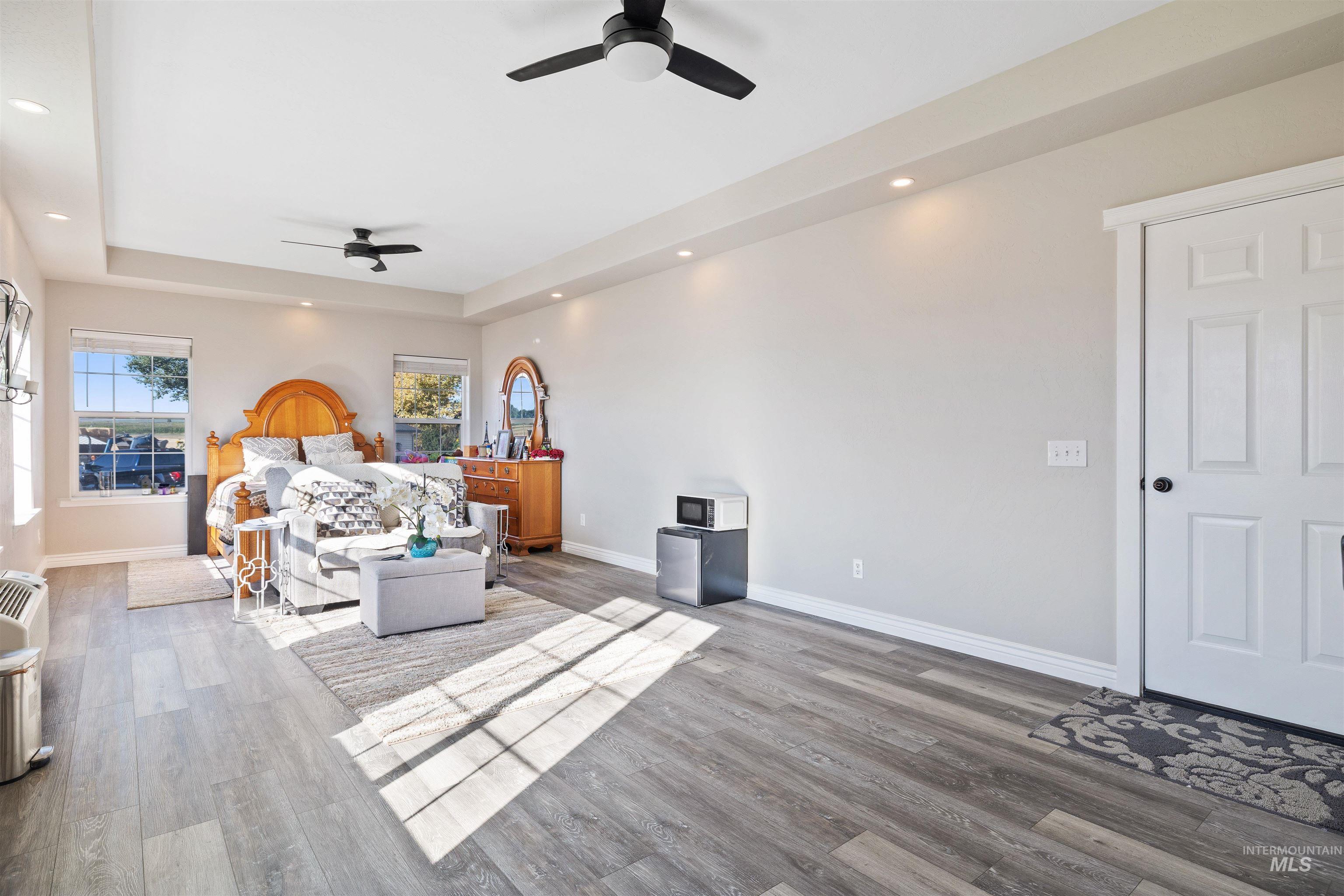 Bedroom featuring a raised ceiling, wood finished floors, recessed lighting, and ceiling fan