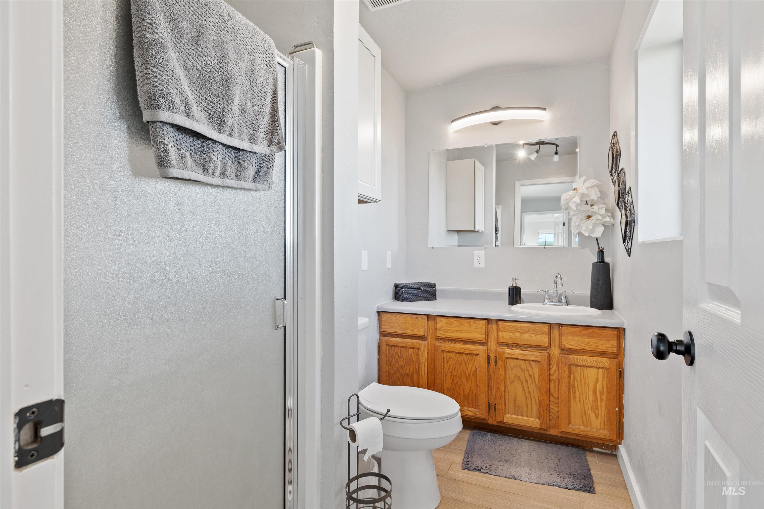 Bathroom featuring a stall shower, vanity, and light wood-type flooring