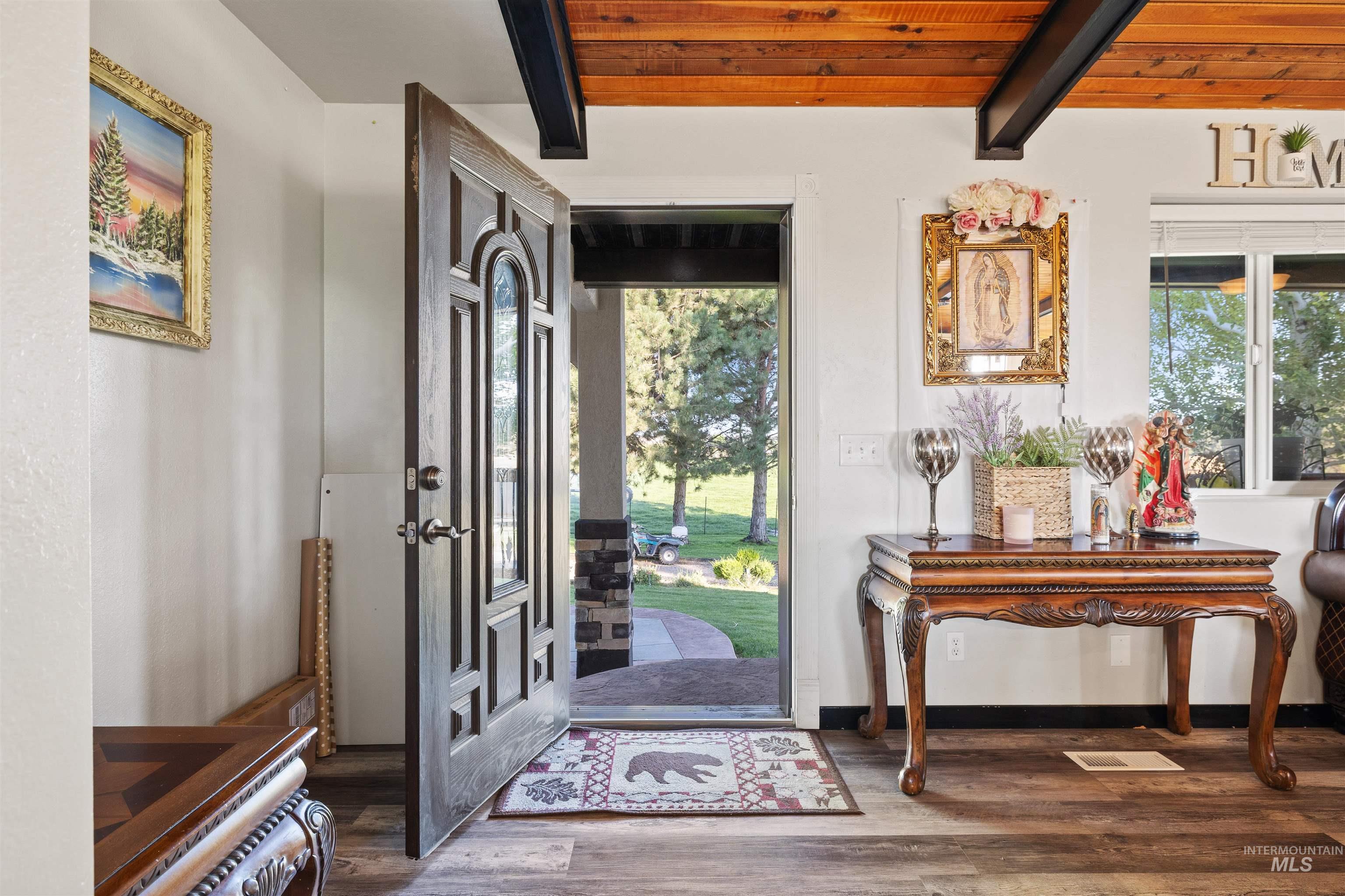 Entrance foyer with dark wood-style flooring and a wood ceiling with exposed beams