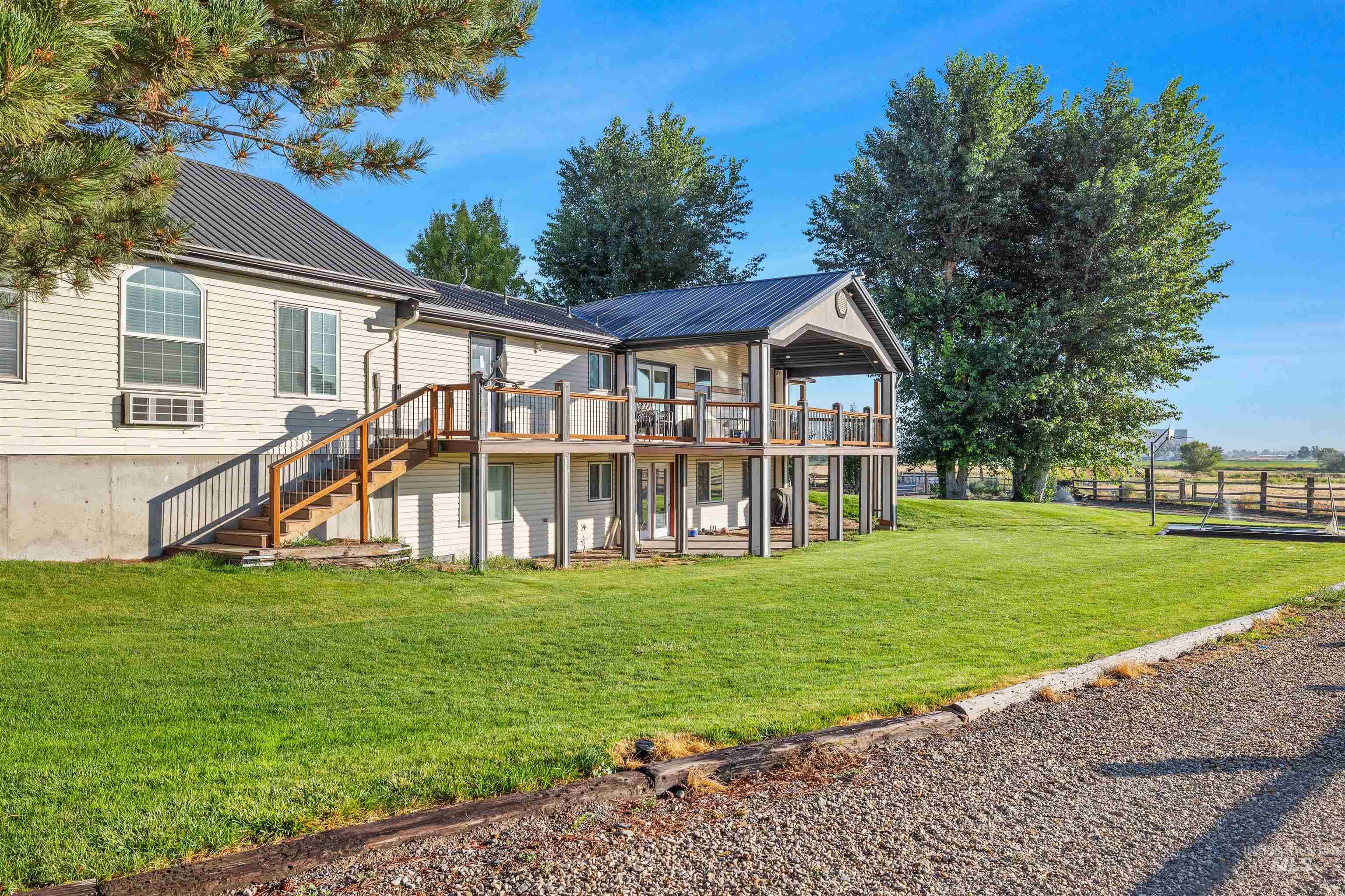 Rear view of house featuring a metal roof, stairway, a deck, a lawn, and a standing seam roof