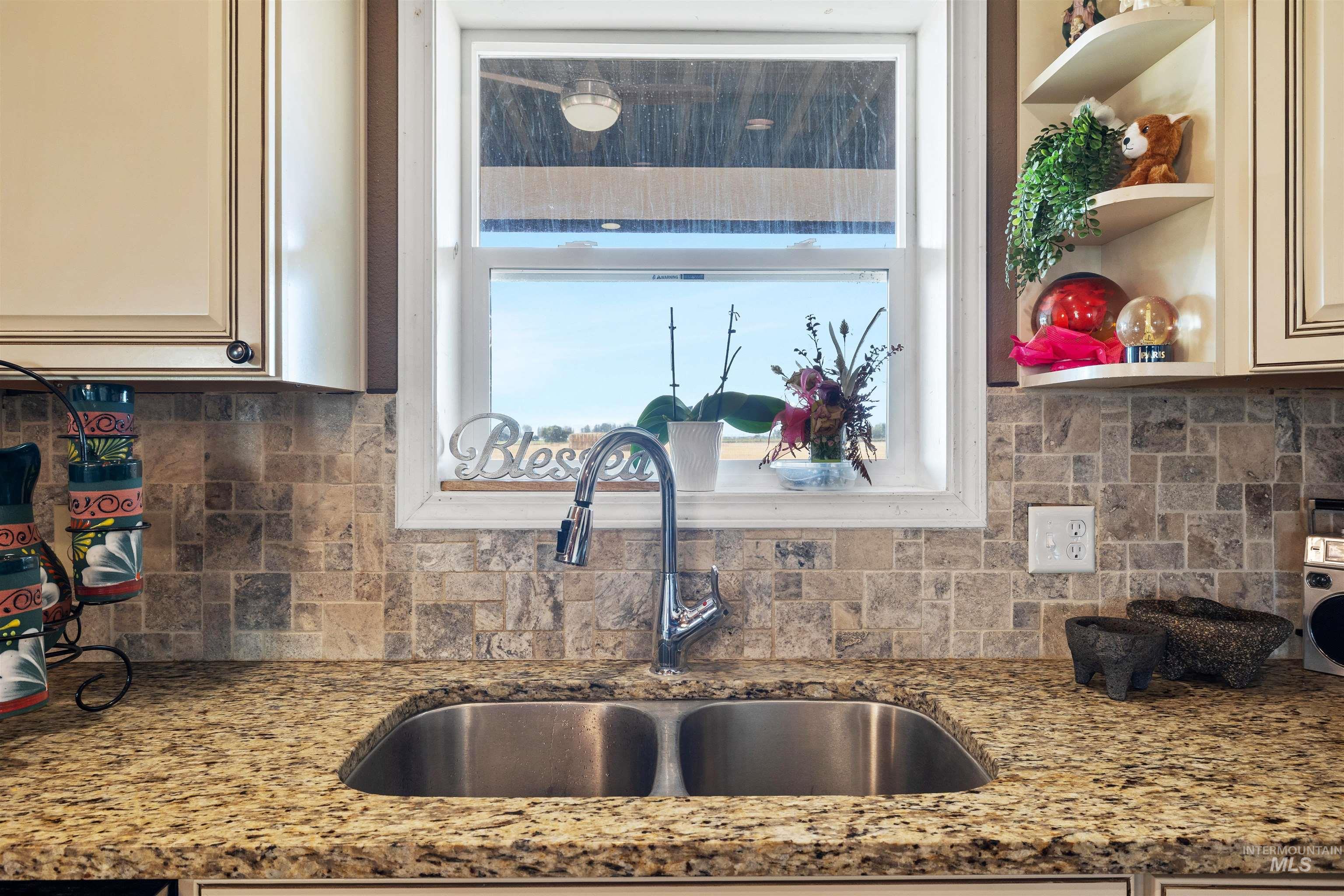 Kitchen with decorative backsplash, light stone countertops, open shelves, and cream cabinets