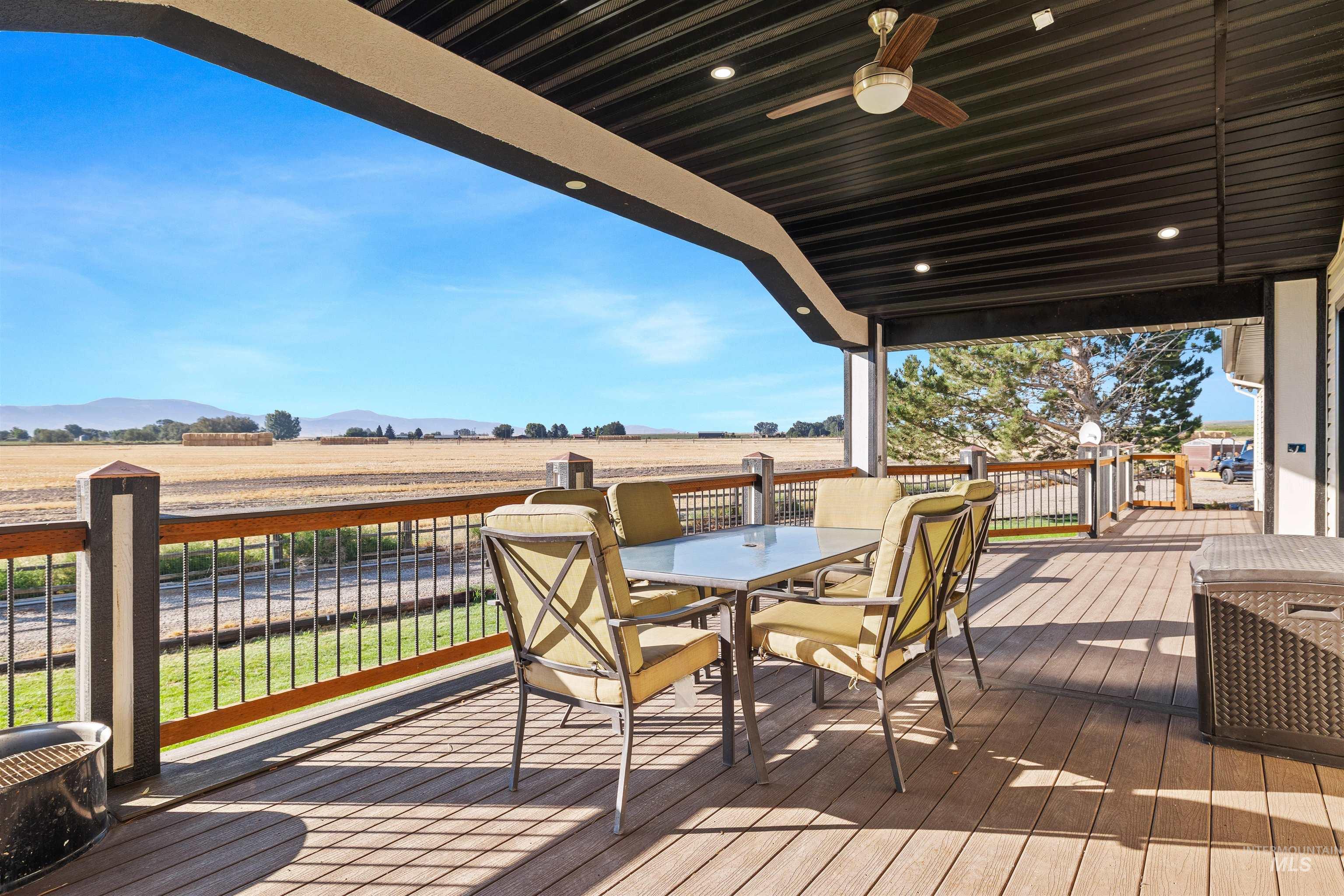 Wooden deck with a view of countryside, outdoor dining space, and a ceiling fan