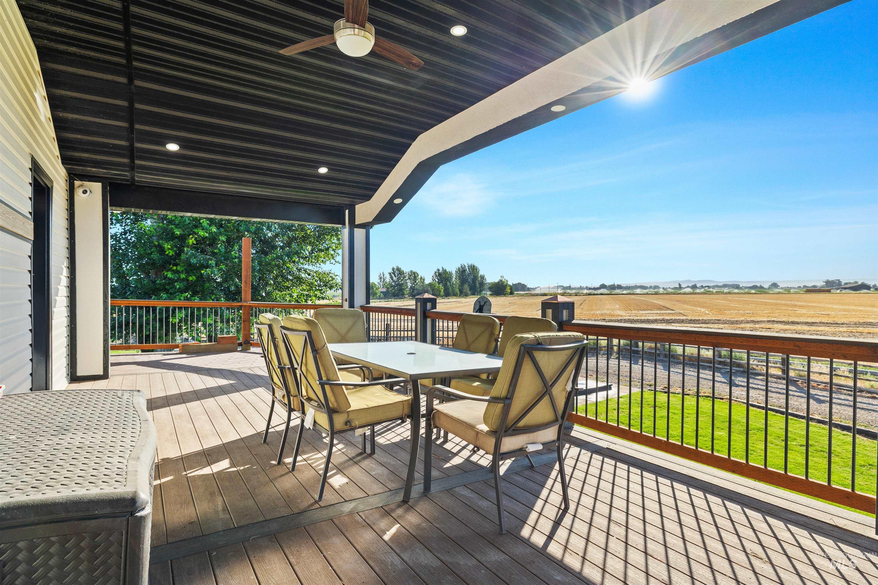 Wooden terrace with outdoor dining space, a ceiling fan, and a rural view