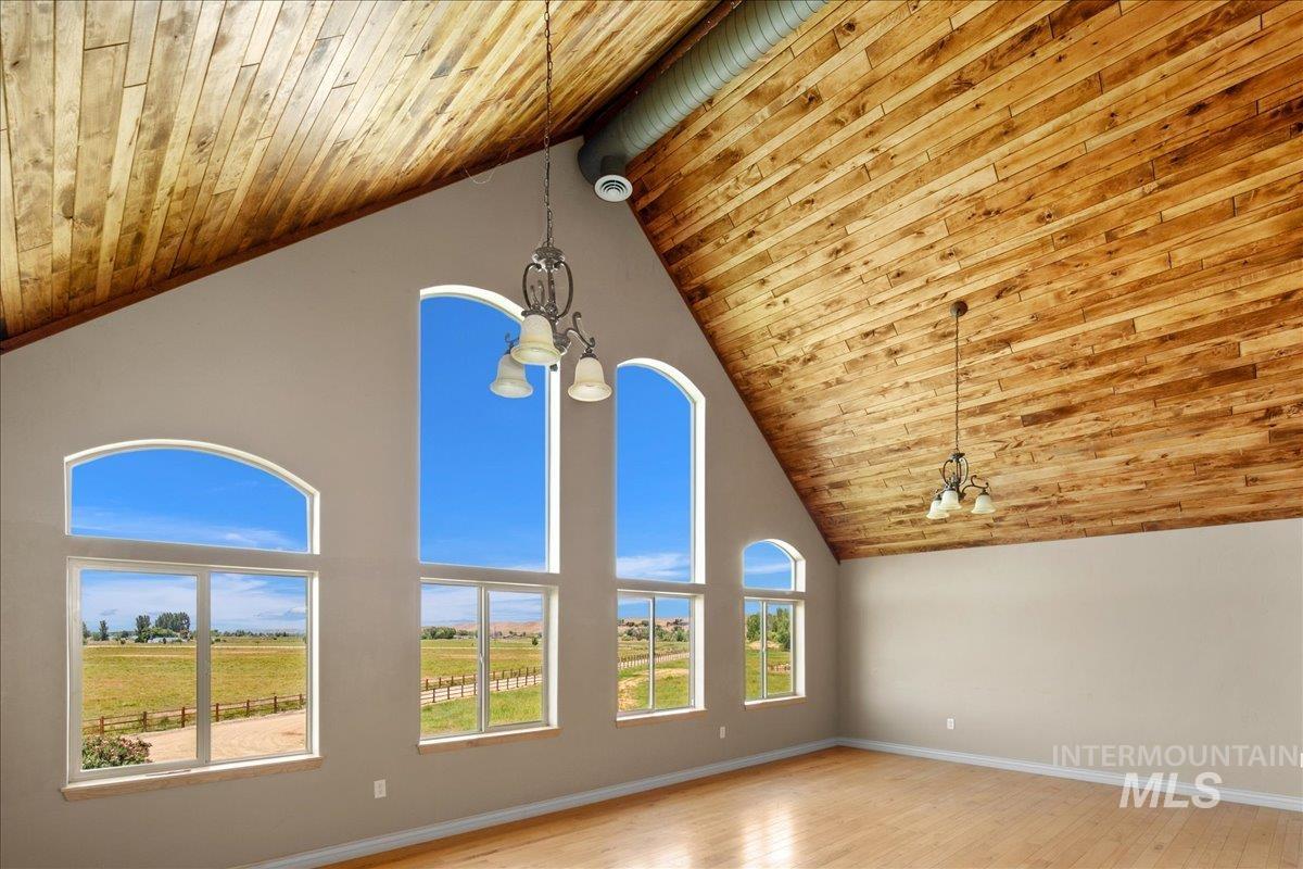 Unfurnished room with wood ceiling, a chandelier, wood finished floors, and high vaulted ceiling