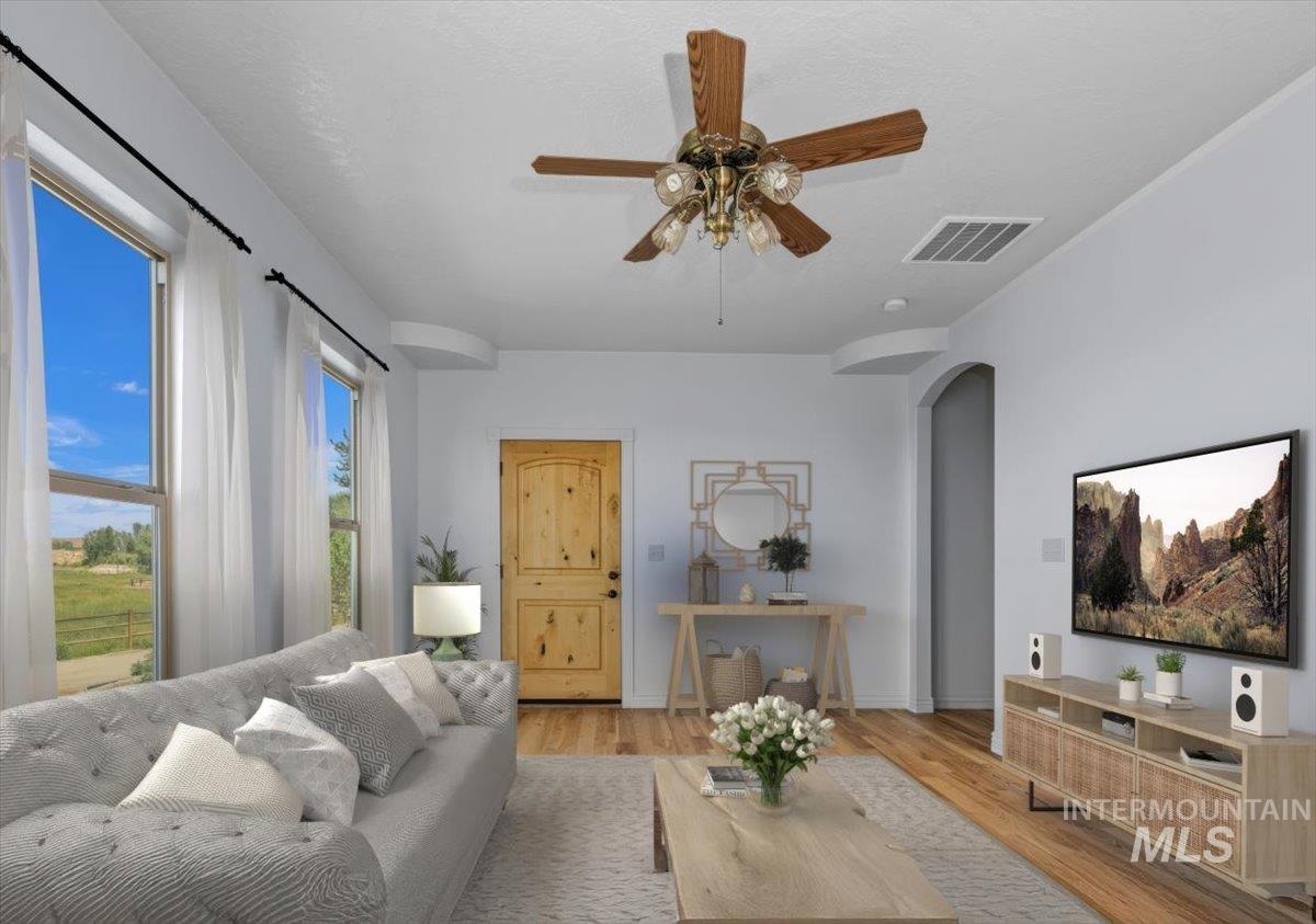 Living area with arched walkways, light wood-style floors, and a ceiling fan