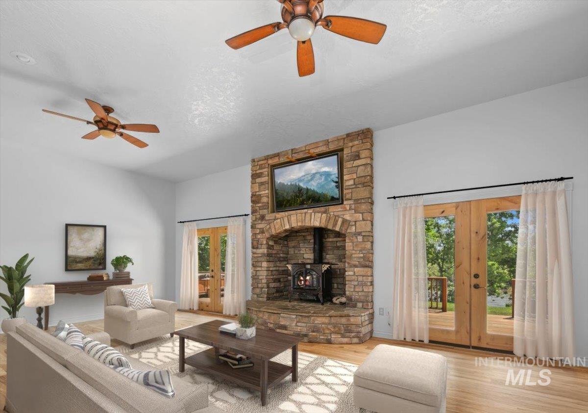Living area featuring a wood stove, french doors, wood finished floors, and a ceiling fan
