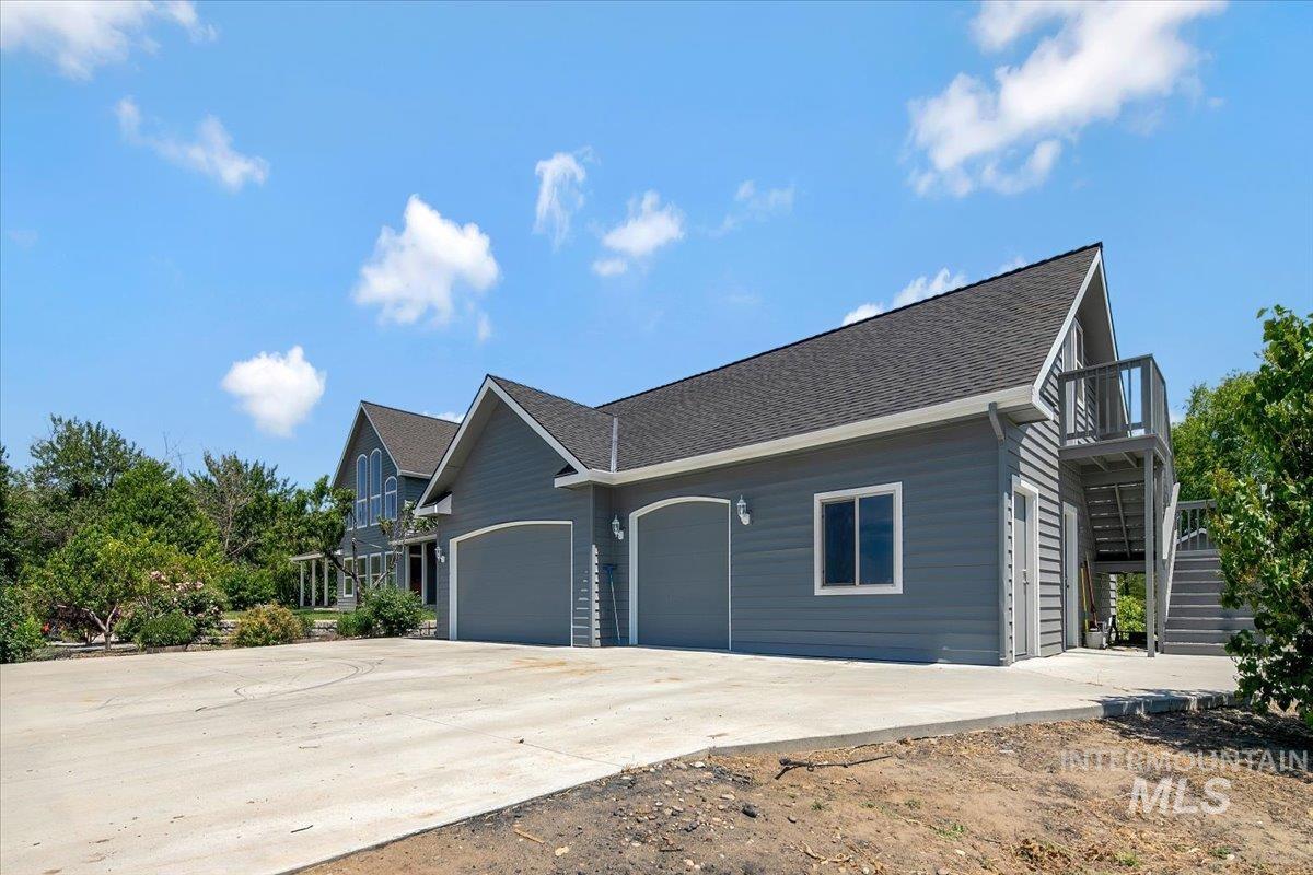 View of property exterior with stairs, a garage, driveway, and roof with shingles