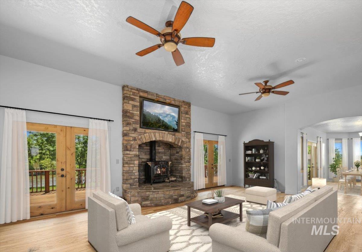 Living area featuring french doors, a ceiling fan, a textured ceiling, a wood stove, and wood finished floors