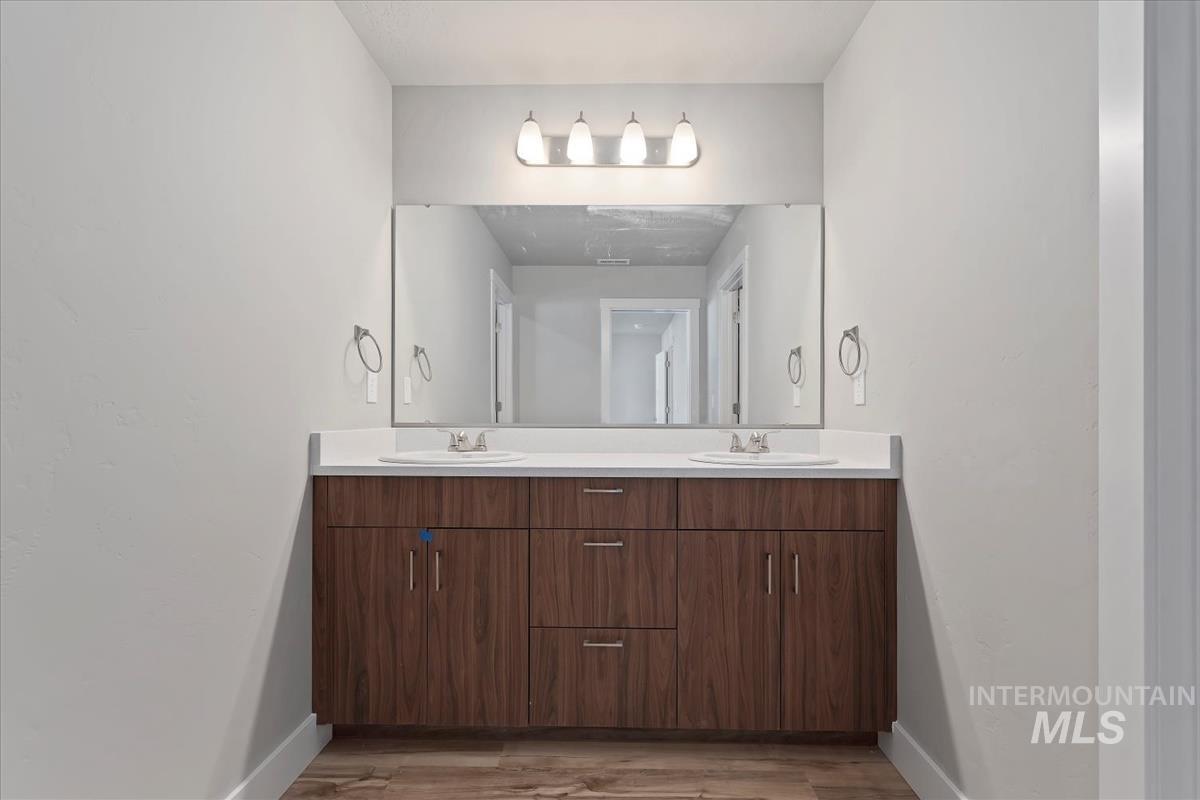 Full bath featuring double vanity and light wood finished floors