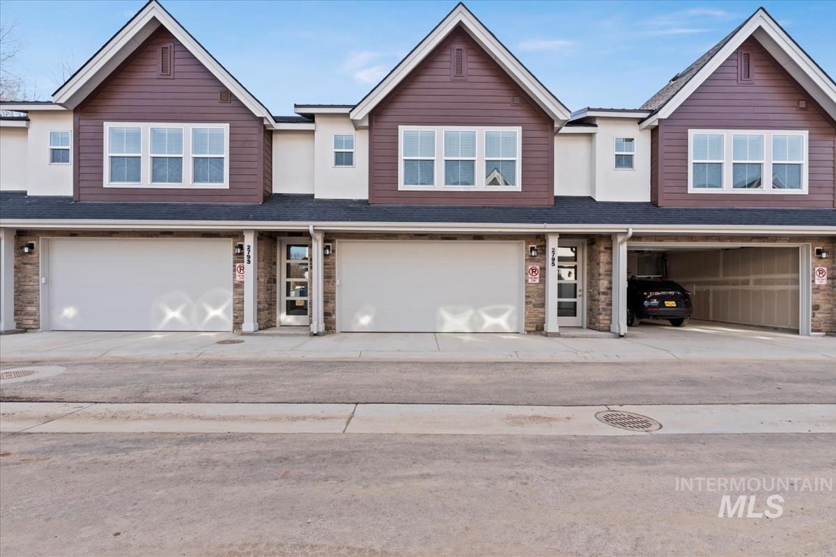 Traditional-style house featuring roof with shingles, stone siding, and driveway