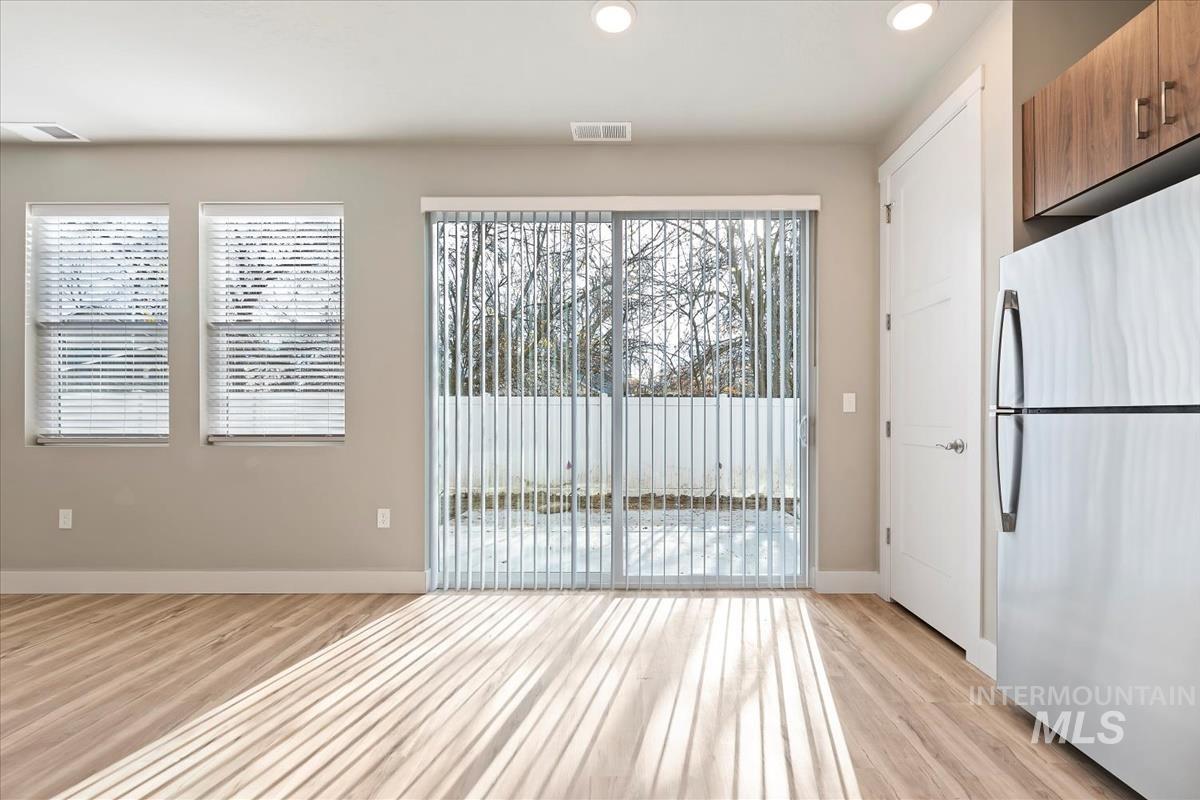 Kitchen with freestanding refrigerator, light wood-style floors, healthy amount of natural light, recessed lighting, and brown cabinets