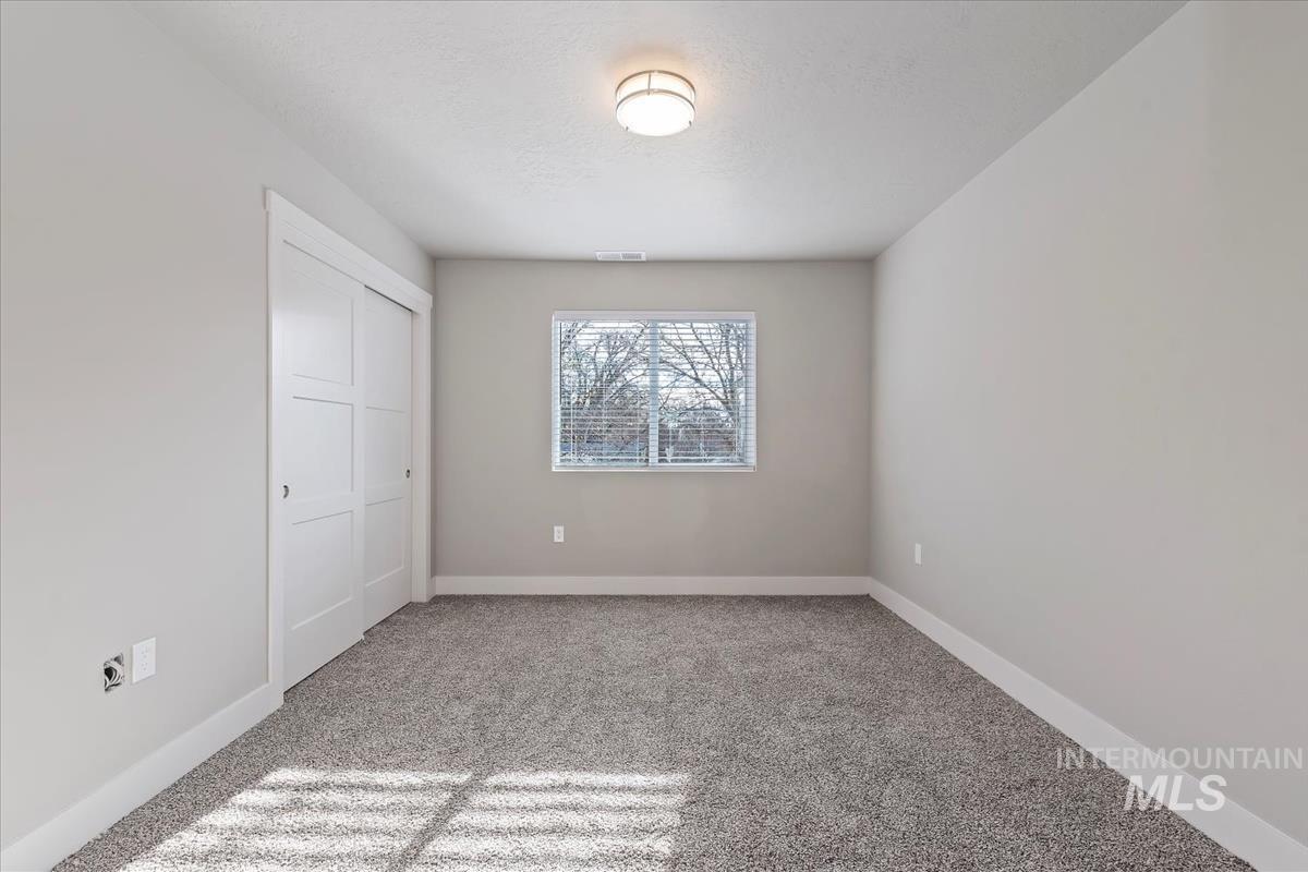 Unfurnished bedroom with a closet, light colored carpet, and a textured ceiling