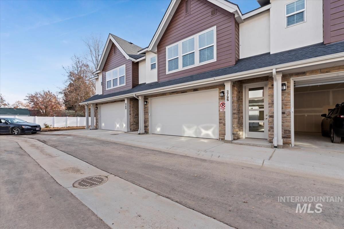 Traditional-style house with stone siding, a garage, and a shingled roof
