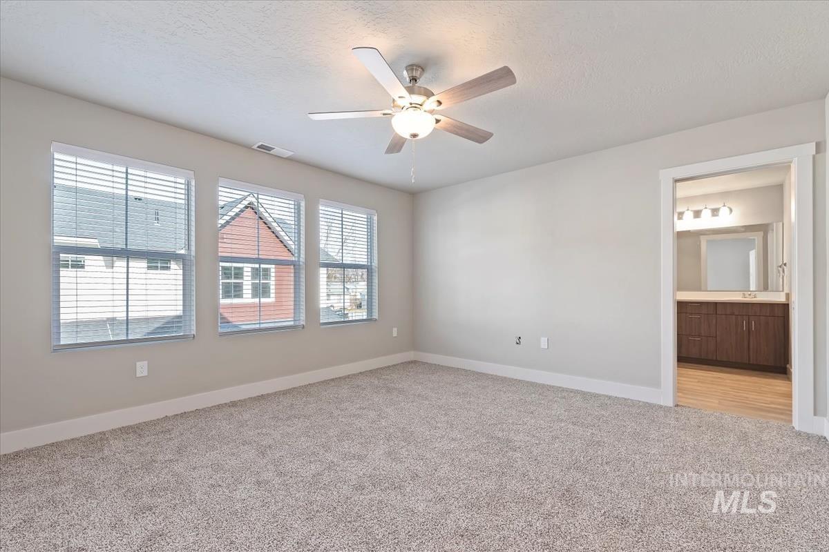 Spare room with light colored carpet, a textured ceiling, and a ceiling fan