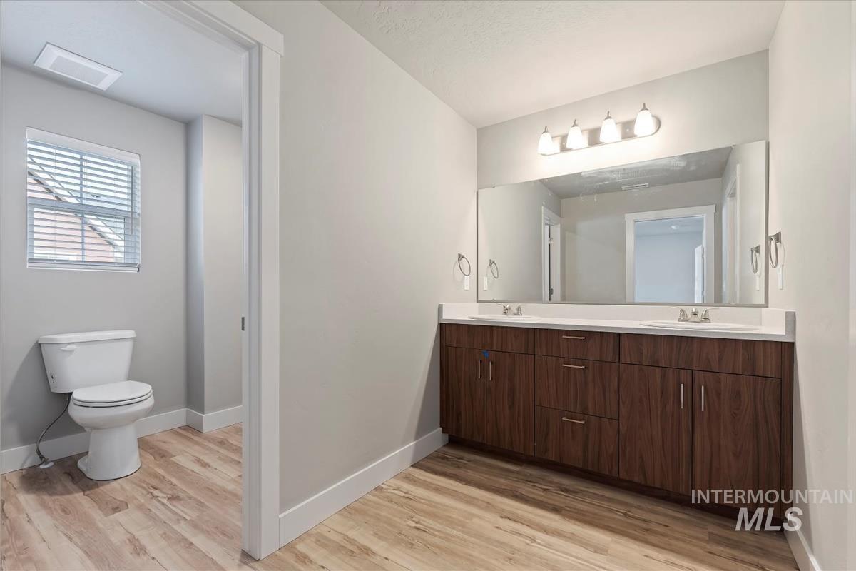 Full bathroom with double vanity and light wood-type flooring