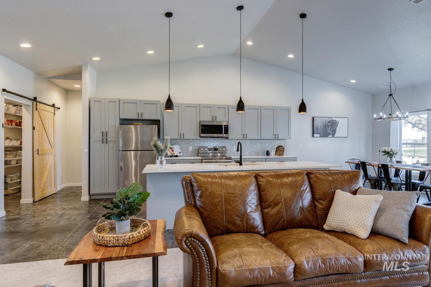 Living area with a barn door, a chandelier, and high vaulted ceiling