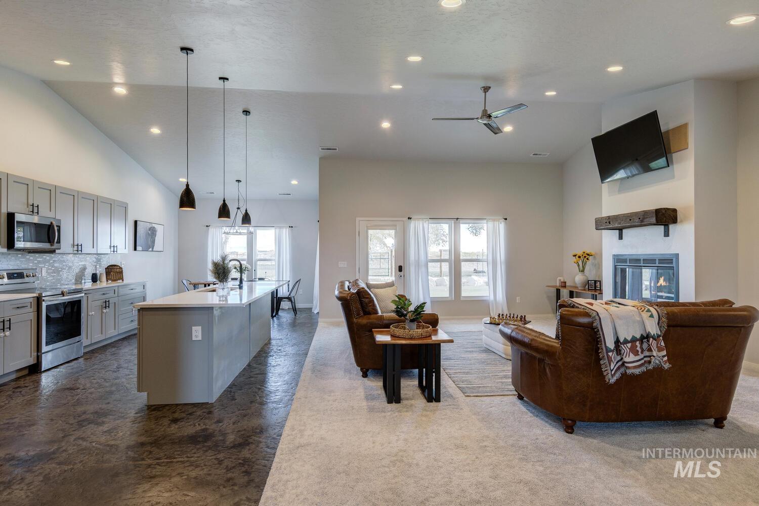 Living room with a glass covered fireplace, recessed lighting, high vaulted ceiling, and ceiling fan