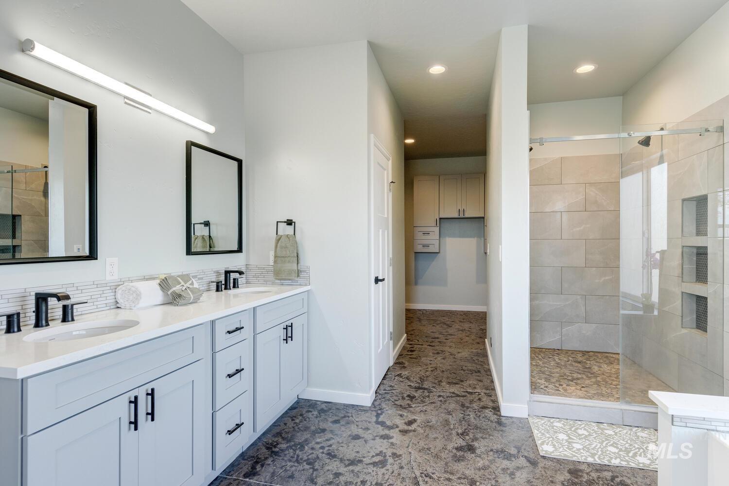 Bathroom featuring walk in shower, double vanity, recessed lighting, and backsplash