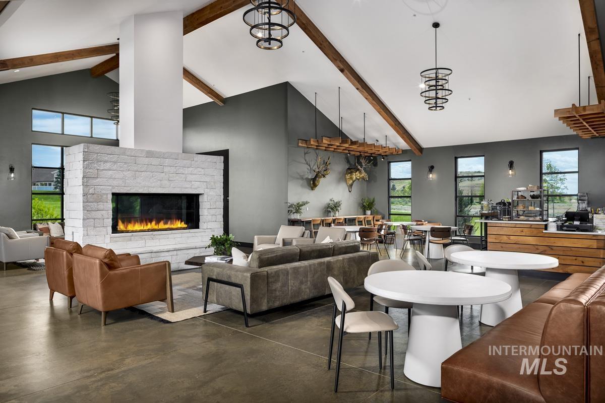 Living area with finished concrete flooring, healthy amount of natural light, beam ceiling, high vaulted ceiling, and a brick fireplace
