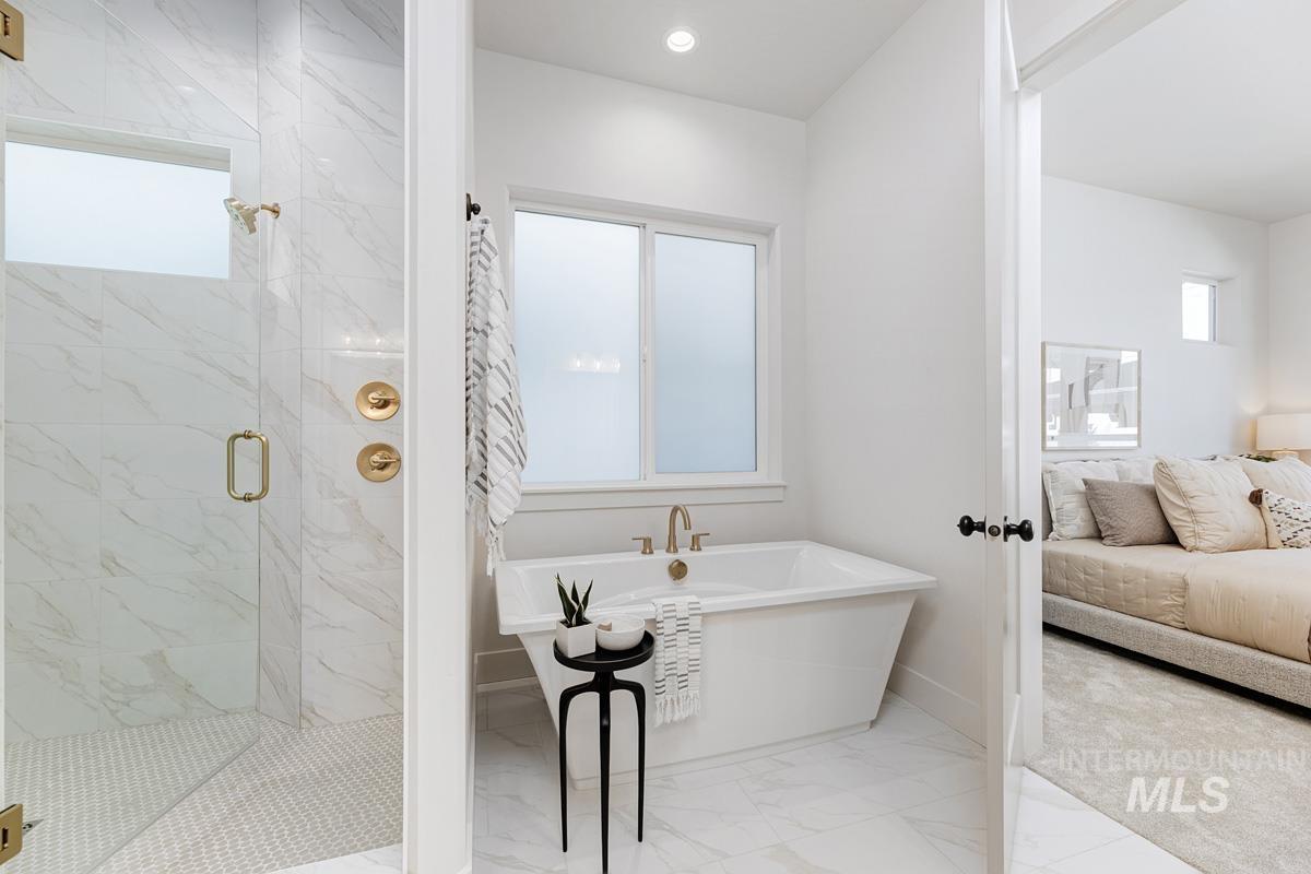 Ensuite bathroom featuring a marble finish shower, light marble finish flooring, and a freestanding bath