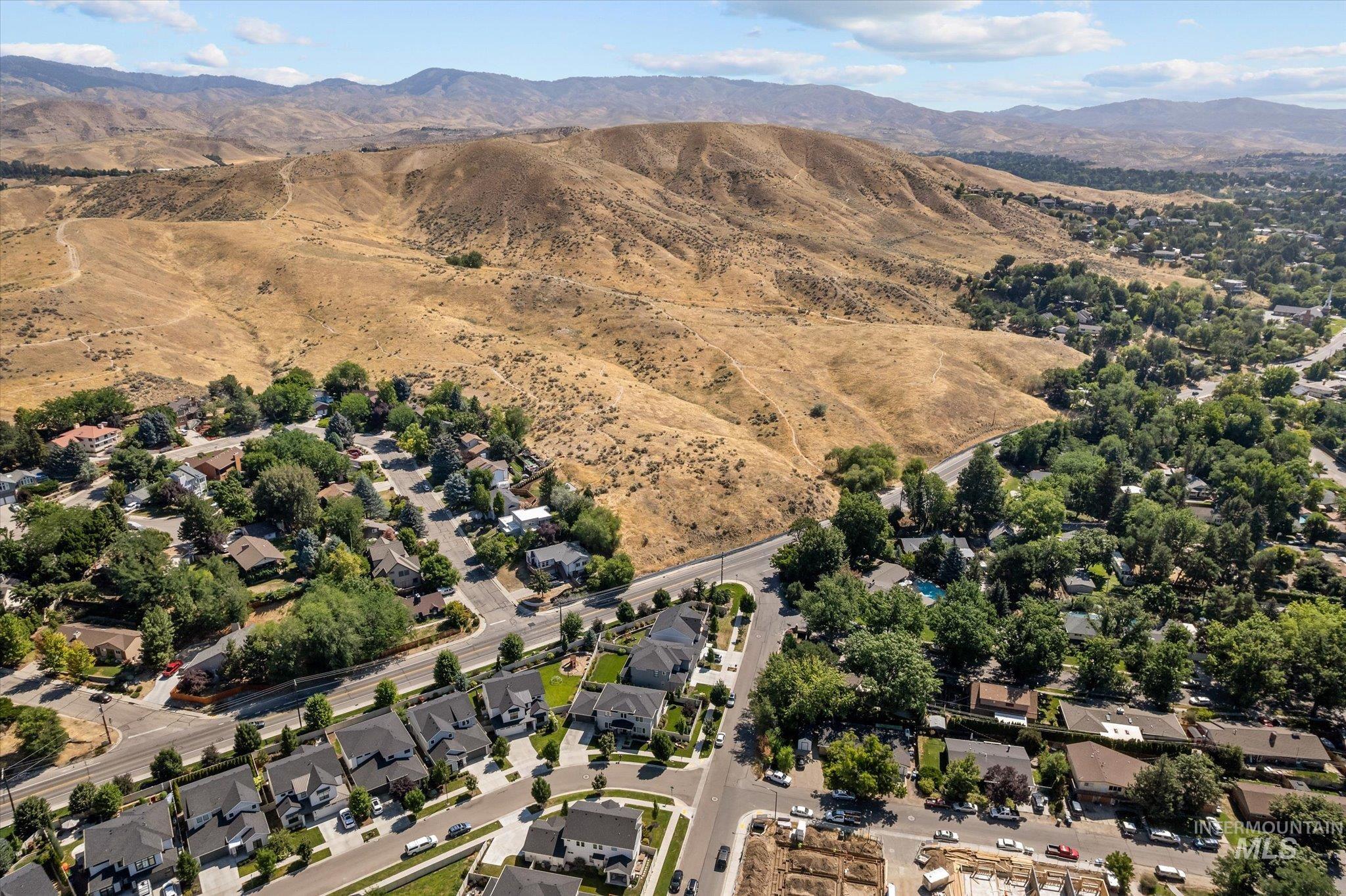 Aerial view of property and surrounding area with nearby suburban area and a mountain backdrop
