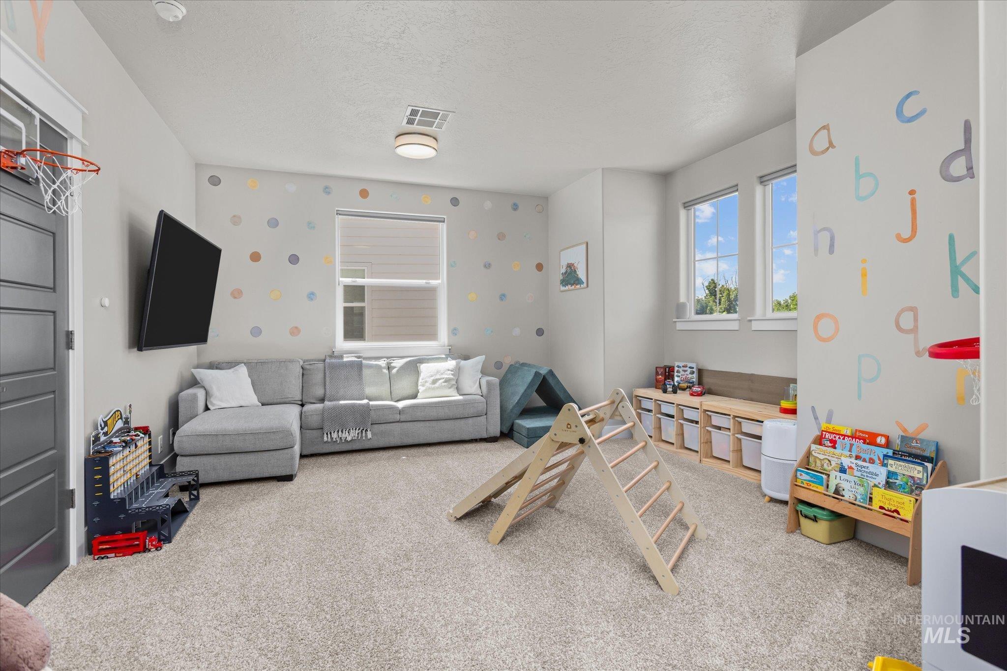 Recreation room with carpet flooring, a textured ceiling, and wallpapered walls